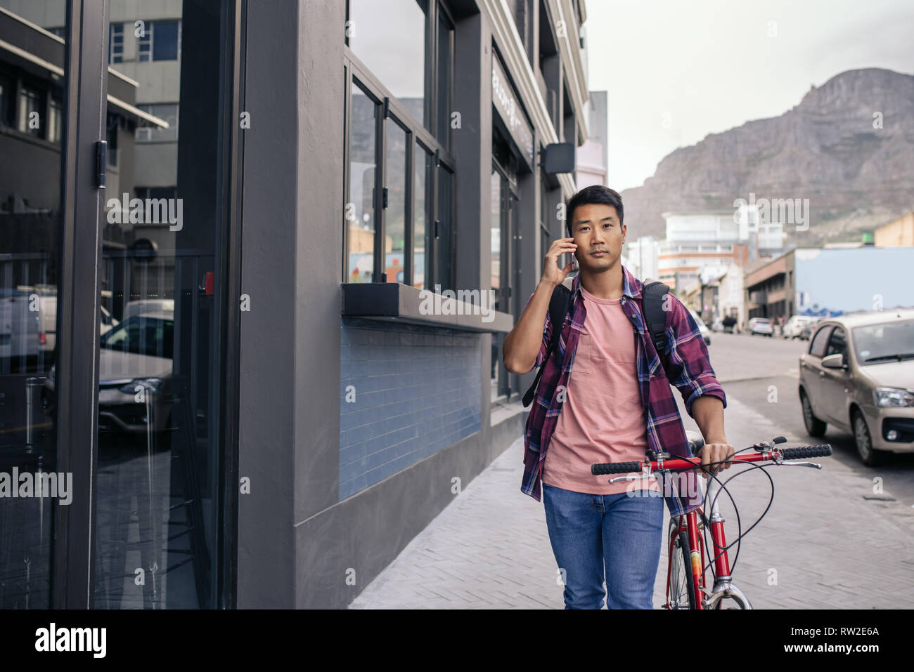 Young man walking with his bike talking on a cellphone Stock Photo