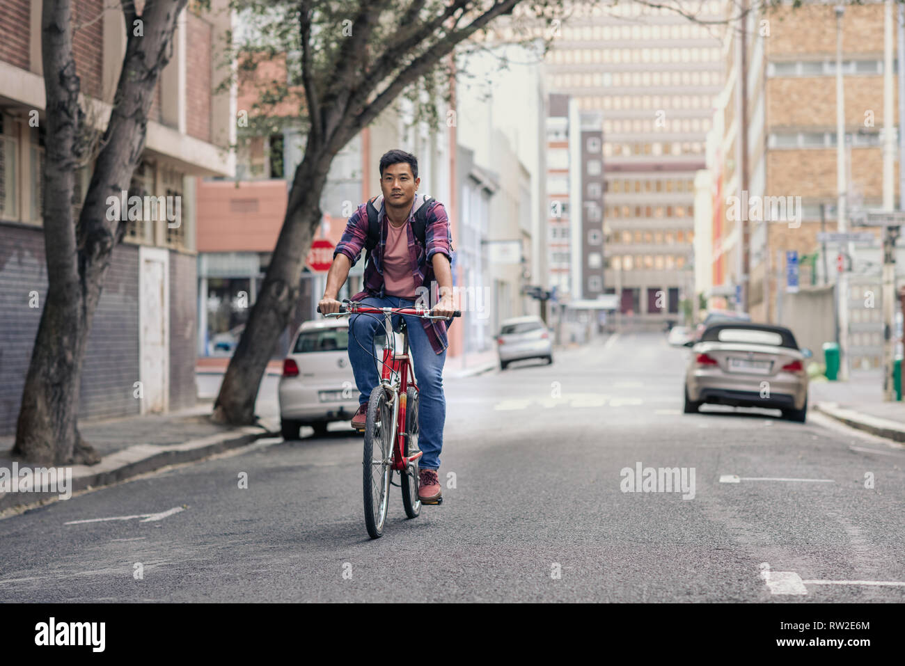 Young Asian man riding his bike on a city street Stock Photo