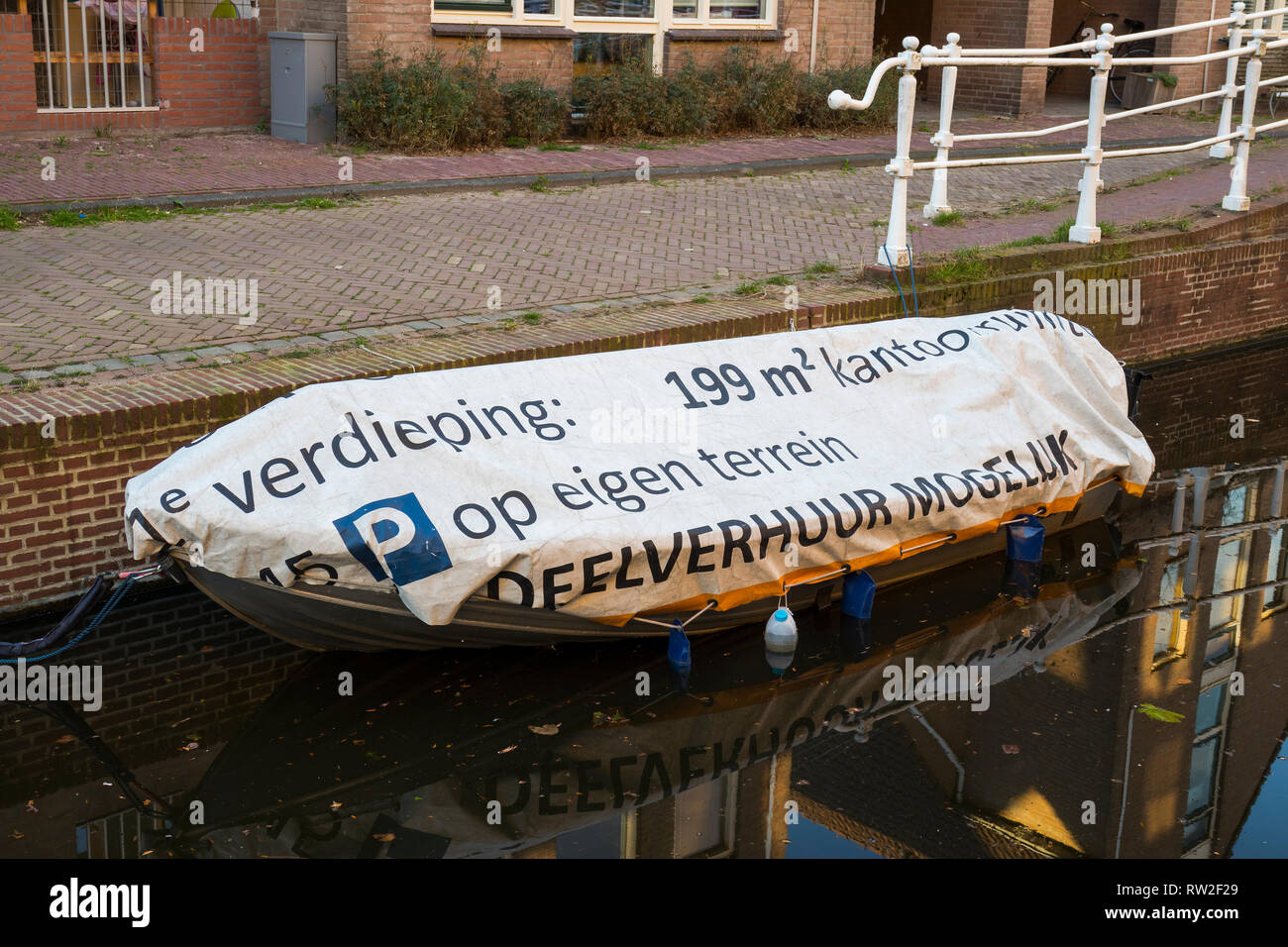 Leiden, Holland - February 25, 2019: Funny Dutch text on the boat tarp, for rent 199 square meters on the first floor Stock Photo