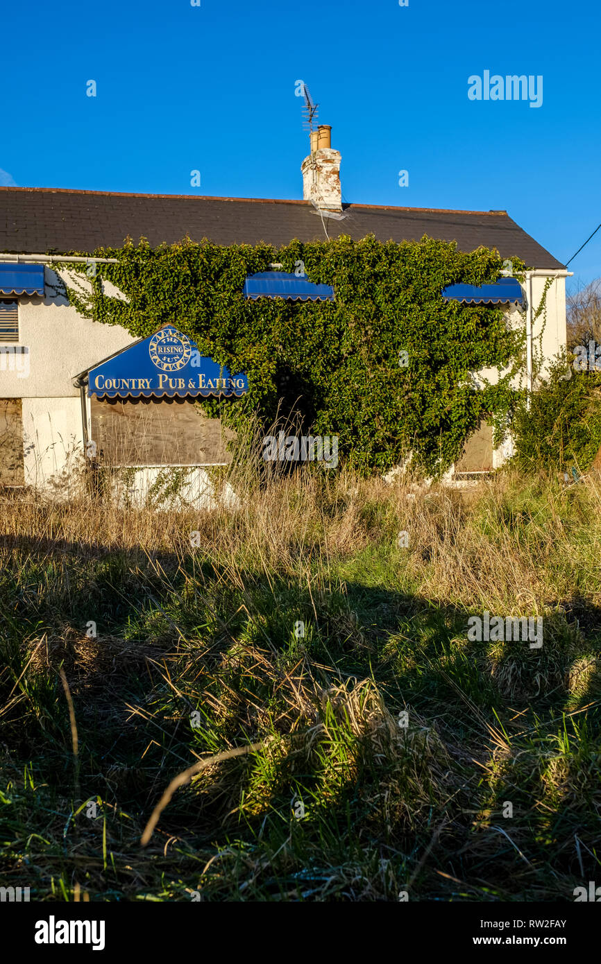 ABANDONED DERELICT PUBLIC HOUSE IN GLOUCESTERSHIRE ENGLAND UK OVERGROWN WITH IVY. Stock Photo