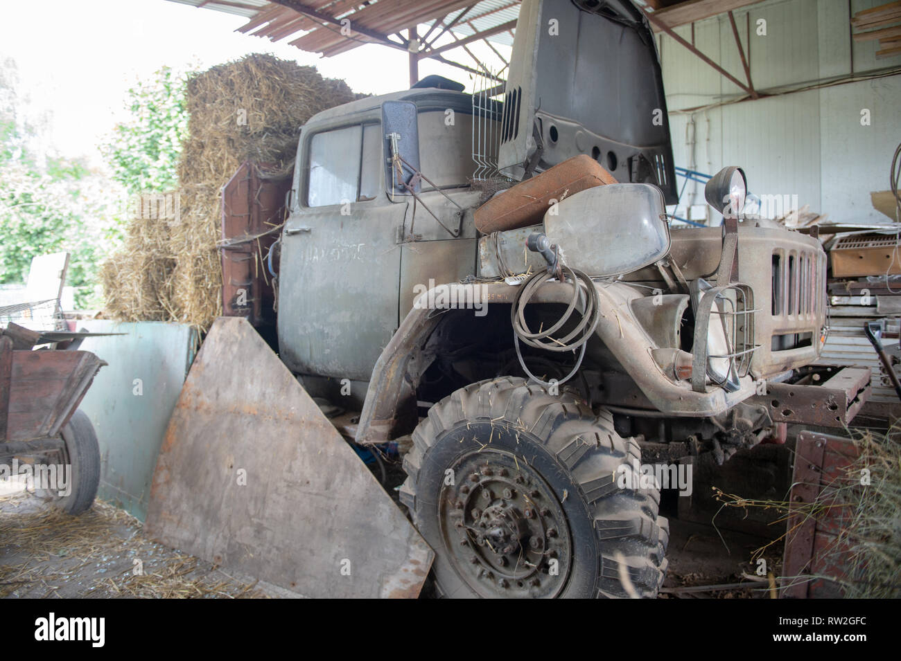 Side angle of dilapidated old farm truck with hay stacked on the back, Pszczółki, Pomeranian Voivodeship, Poland Stock Photo