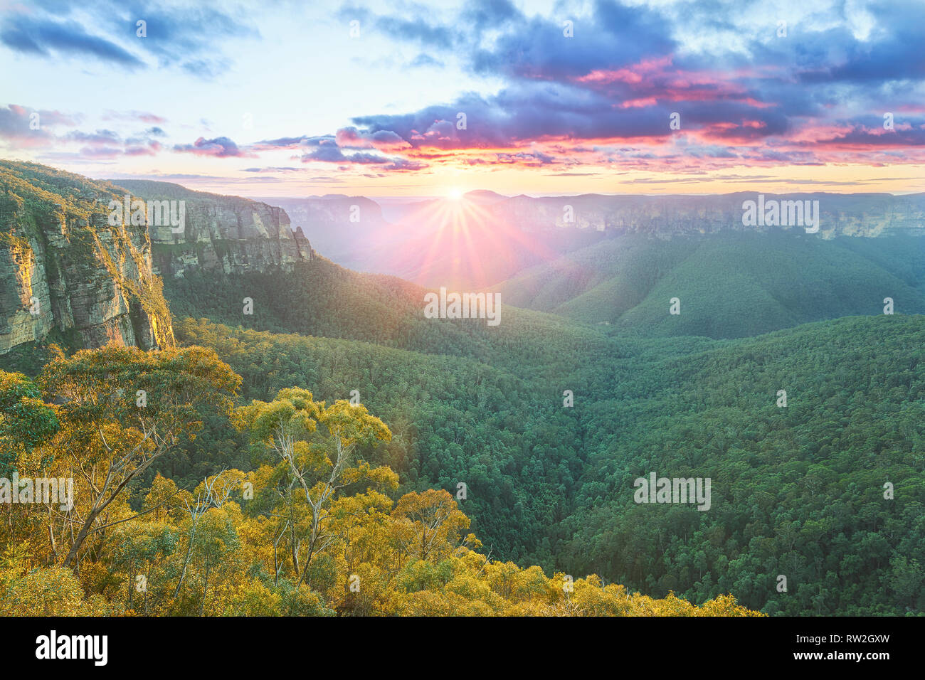 The first rays of lights, illuminates the Blue Mountains range and the eucalyptus trees that overlook the valley below - New South Wales, Australia. Stock Photo