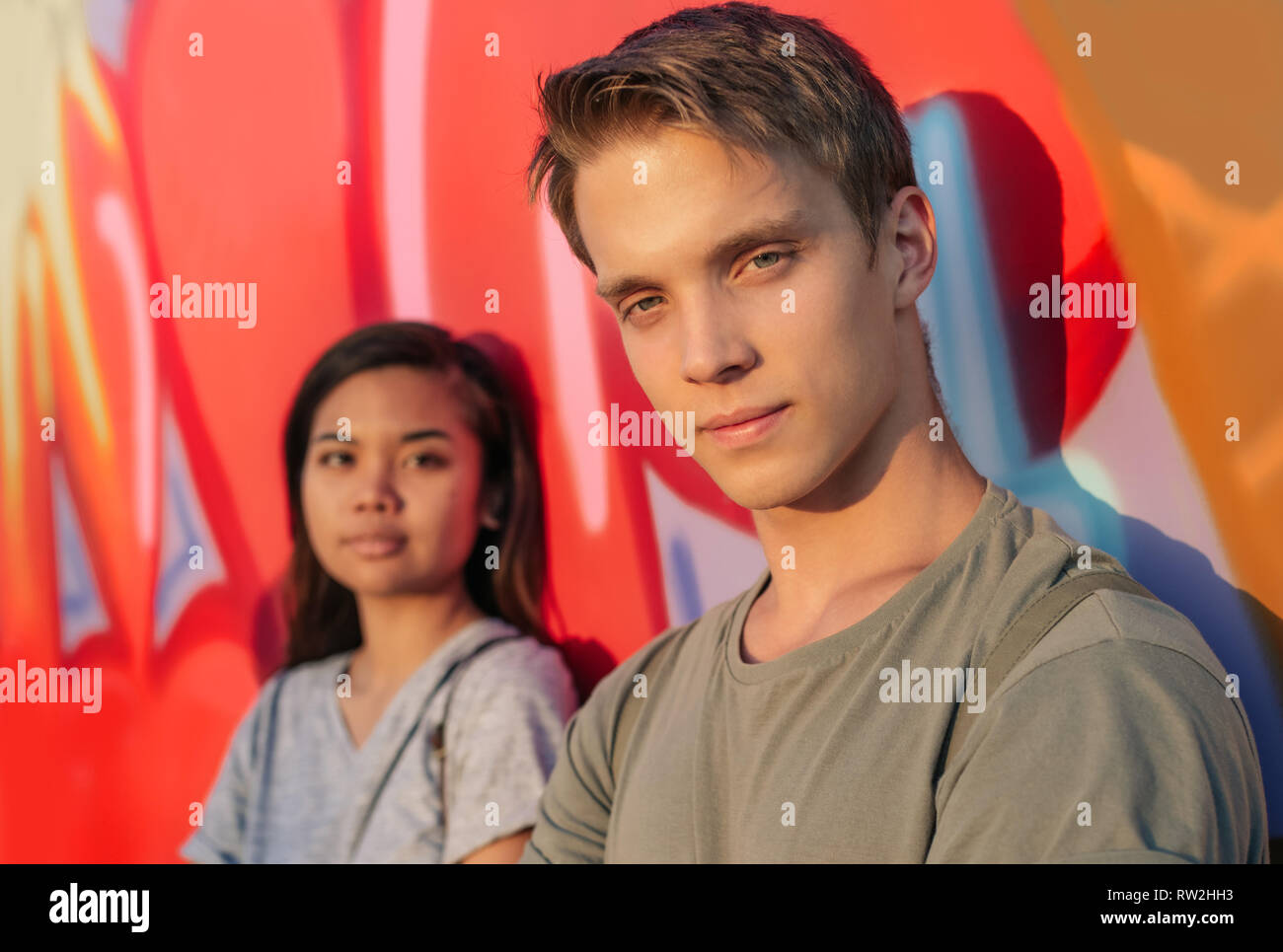 Young couple standing by graffiti in the city Stock Photo