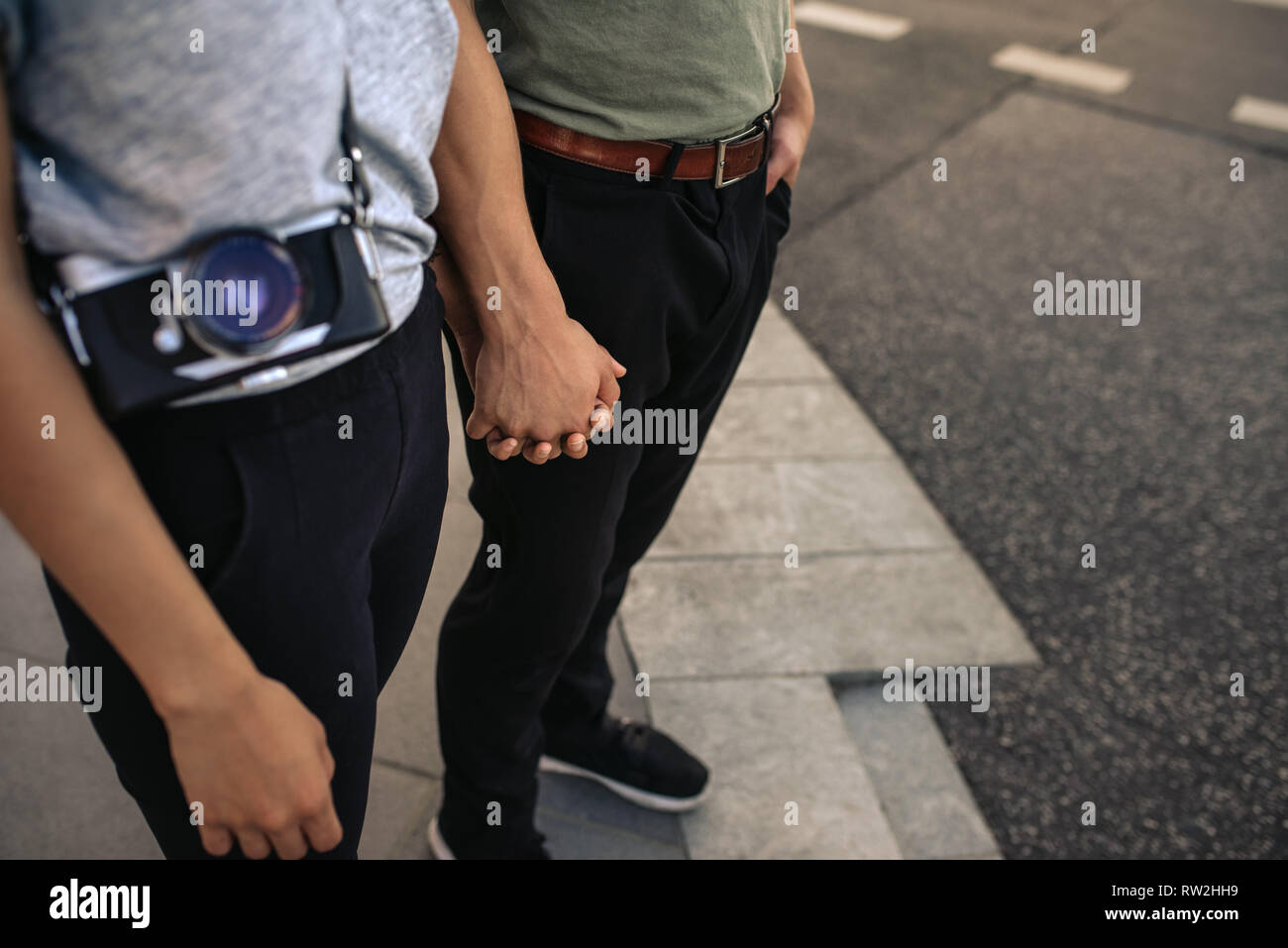 Young couple holding hands while standing on a city sidewalk Stock Photo