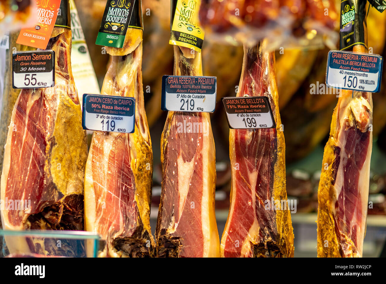 Jam—n IbŽrico de Bellota and Serrano hams hanging at La Boqueria Food Market in Barcelona ,Spain. Jam—n IbŽrico de Bellota hams hanging at La Boqueria Stock Photo