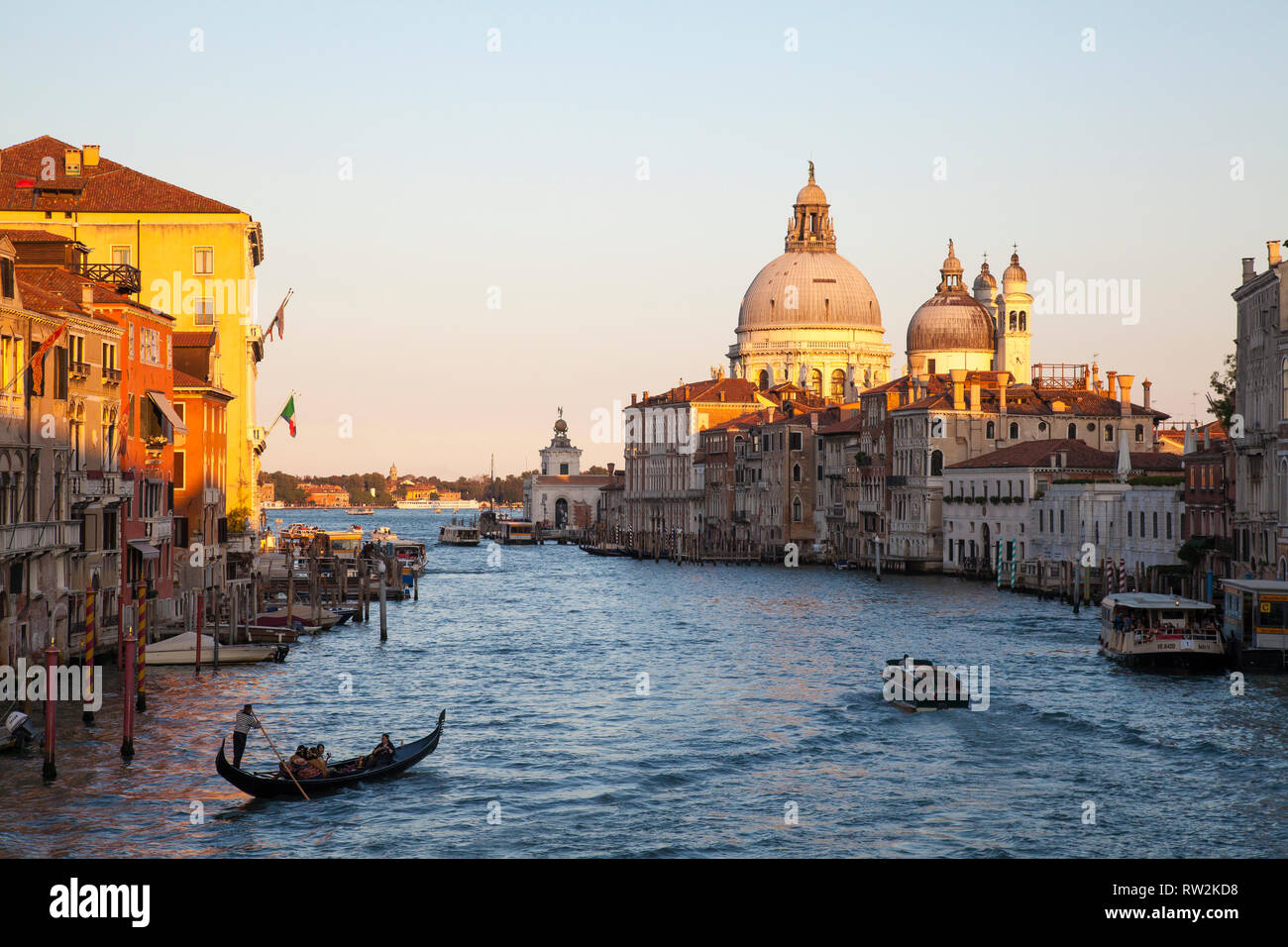 Romantic gondola ride at sunset on the Grand Canal, Venice, Veneto, Italy with golden light and a view to Basilica di Santa Maria della Salute Stock Photo