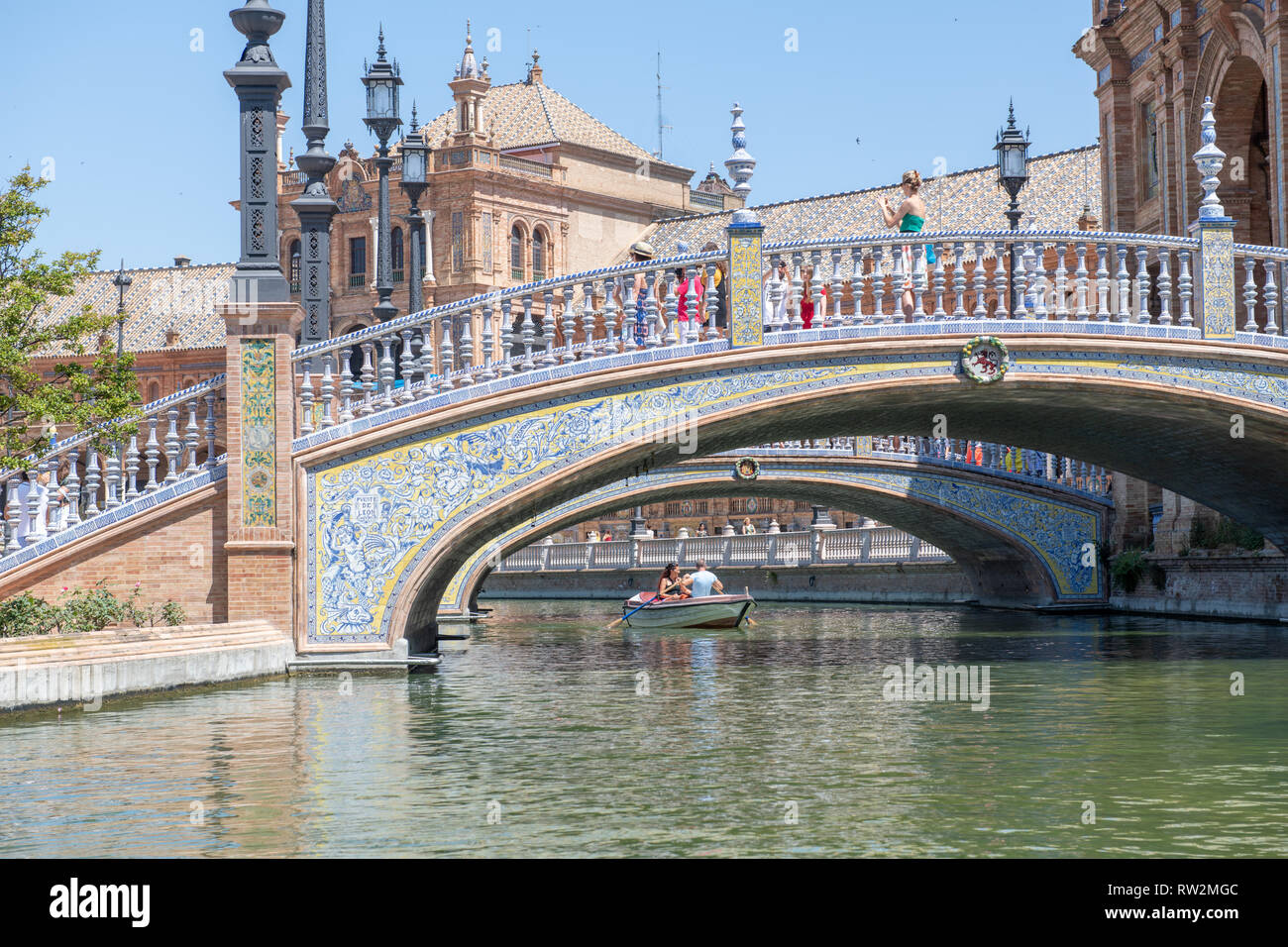 Tourist walk across small bridges over canal in Plaza de Espa–a -Seville , Spain Stock Photo