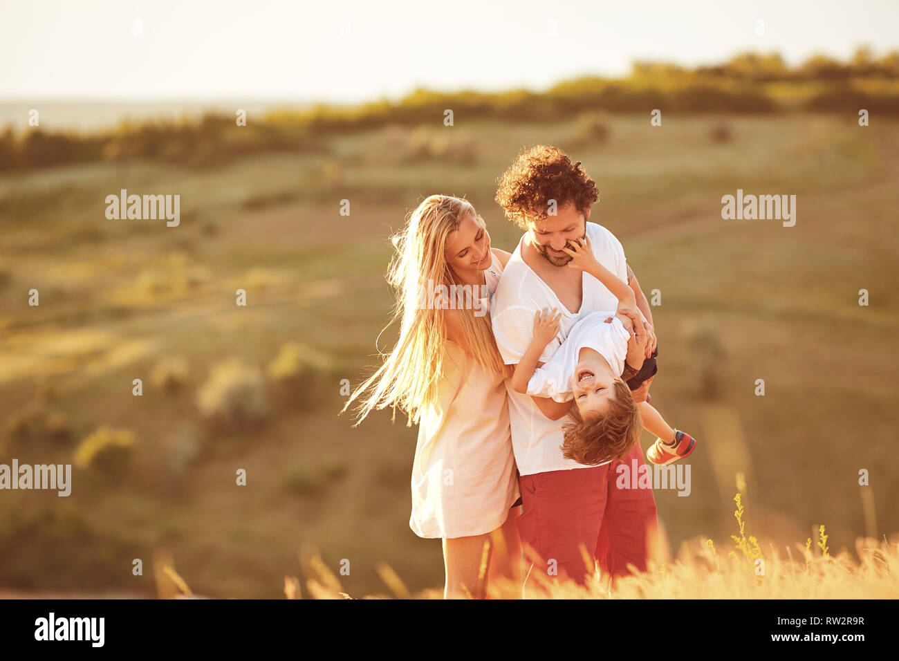 Happy family having fun playing at sunset in nature. Stock Photo