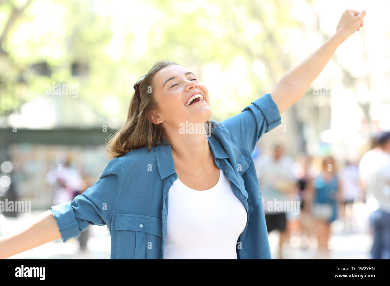 Excited girl celebrating success stretching arms in the street Stock Photo