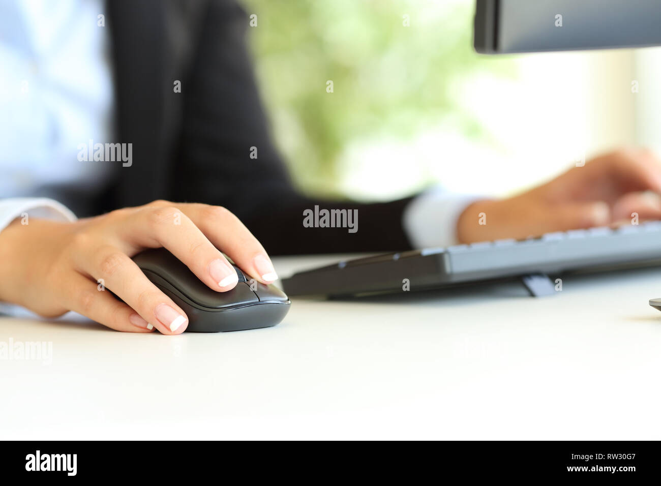 Close up of an office worker hand using computer mouse on a desktop Stock Photo