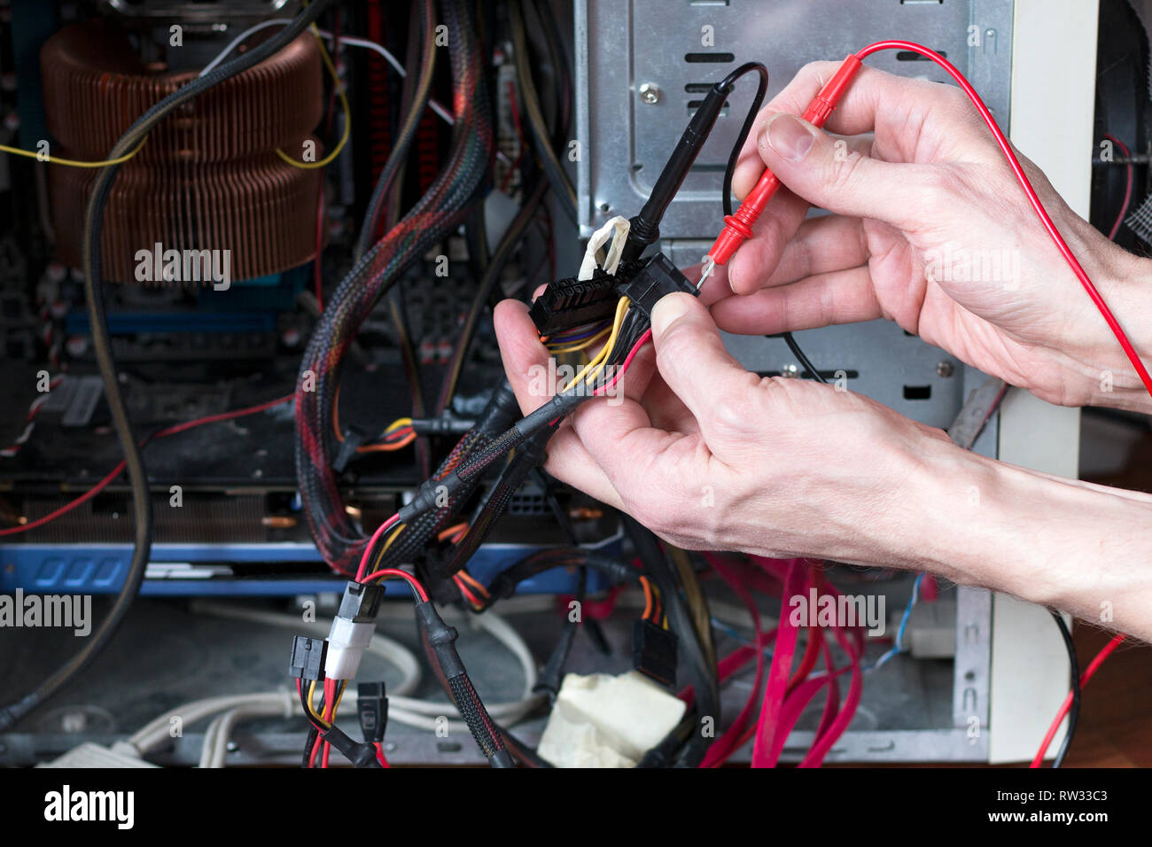 Man is testing the electrical power of power supply. Computer repair