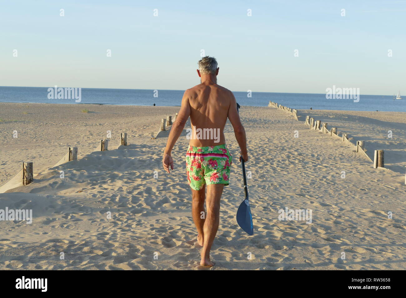 man walking on the beach with paddle on his hand Stock Photo - Alamy