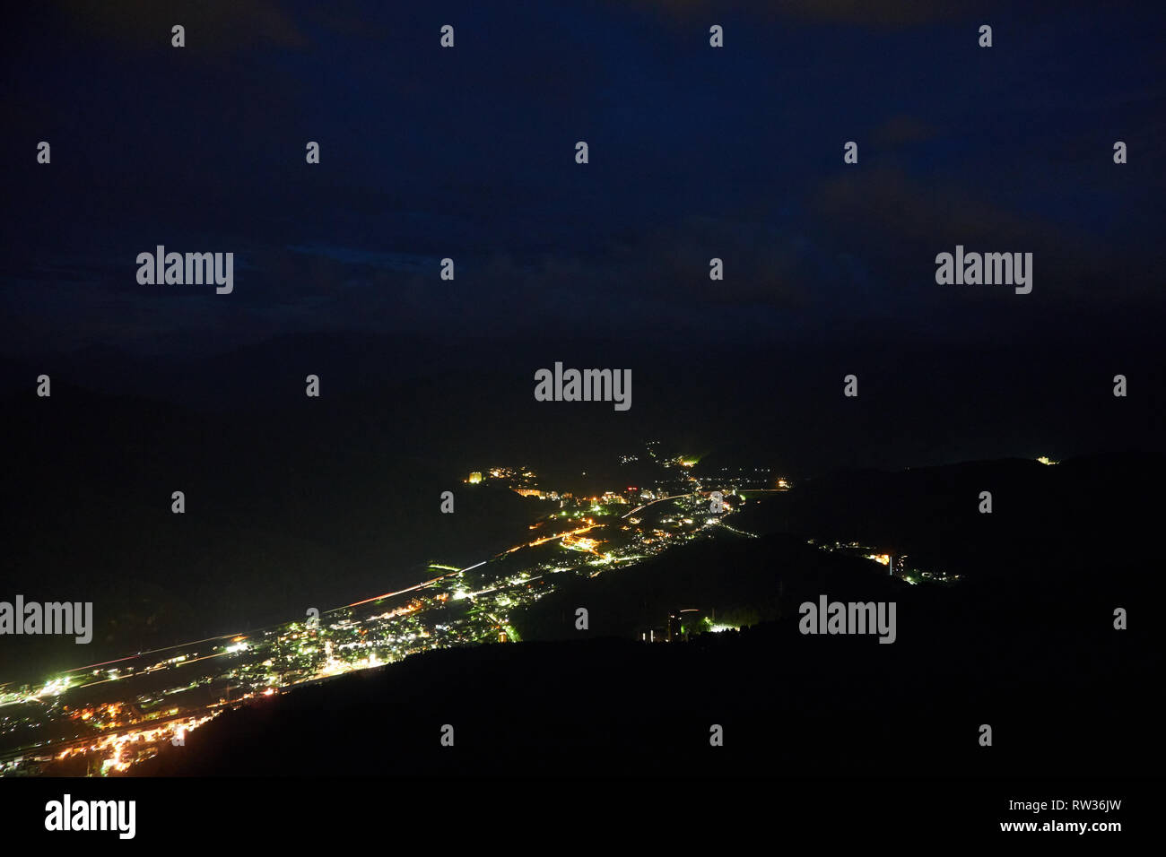 A view of city lights and the Joetsu Expressway in Yuzawa, Niigata, Japan from the top of a nearby mountain. Stock Photo