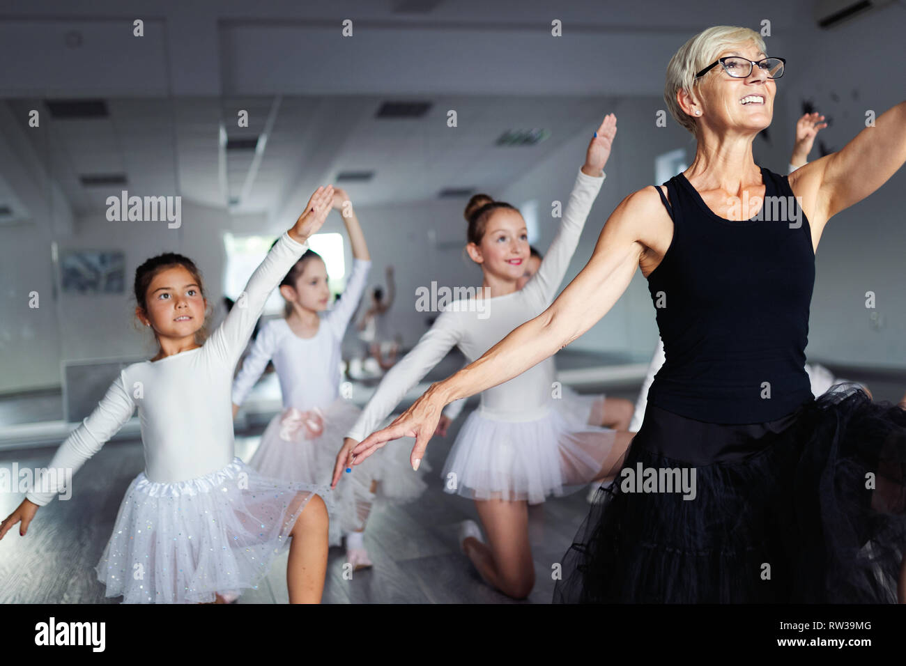 Ballet teacher and students ballerinas exercising in dance class in school Stock Photo