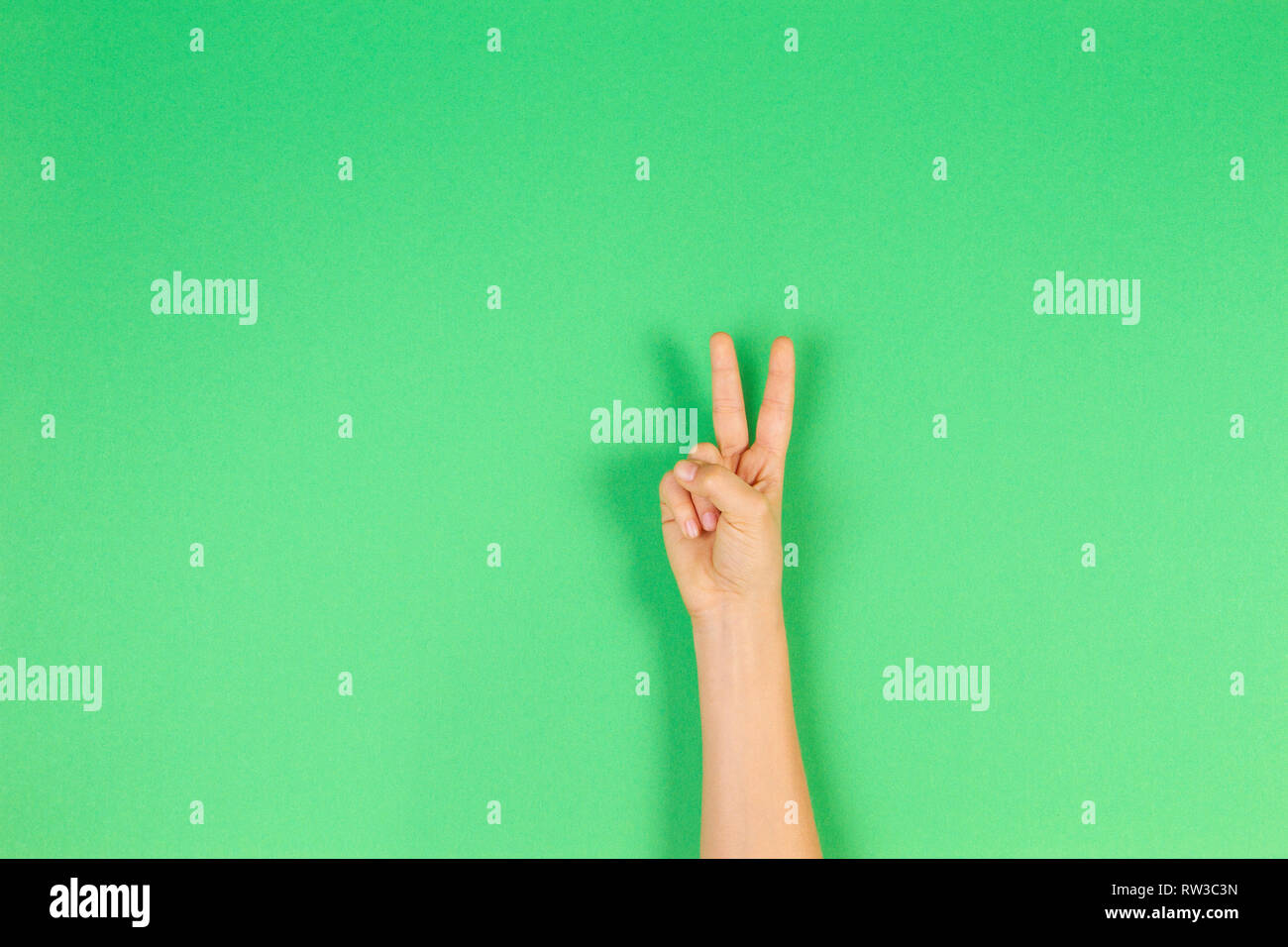 Kid hand with two fingers up on green background. Number two, peace or victory symbol Stock Photo