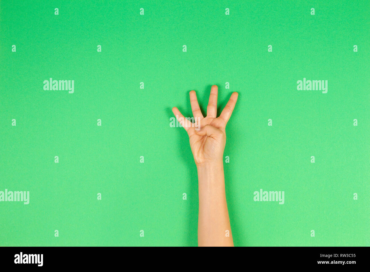 Kid hand showing four fingers on green background Stock Photo