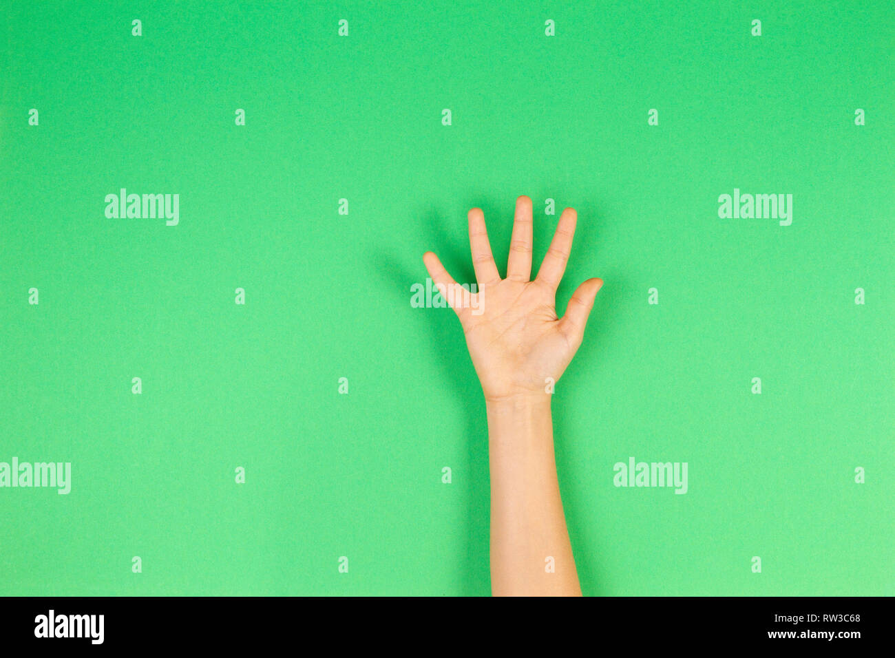 Kid hand palm or showing five fingers on green background Stock Photo