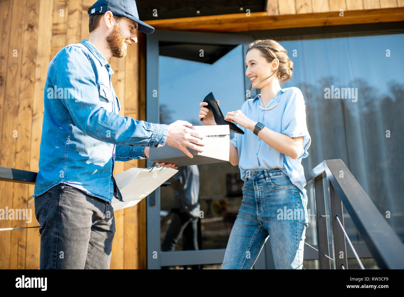 Delivery man bringing shoes home to a young woman client. Buying clothes online and delivery concept Stock Photo Alamy