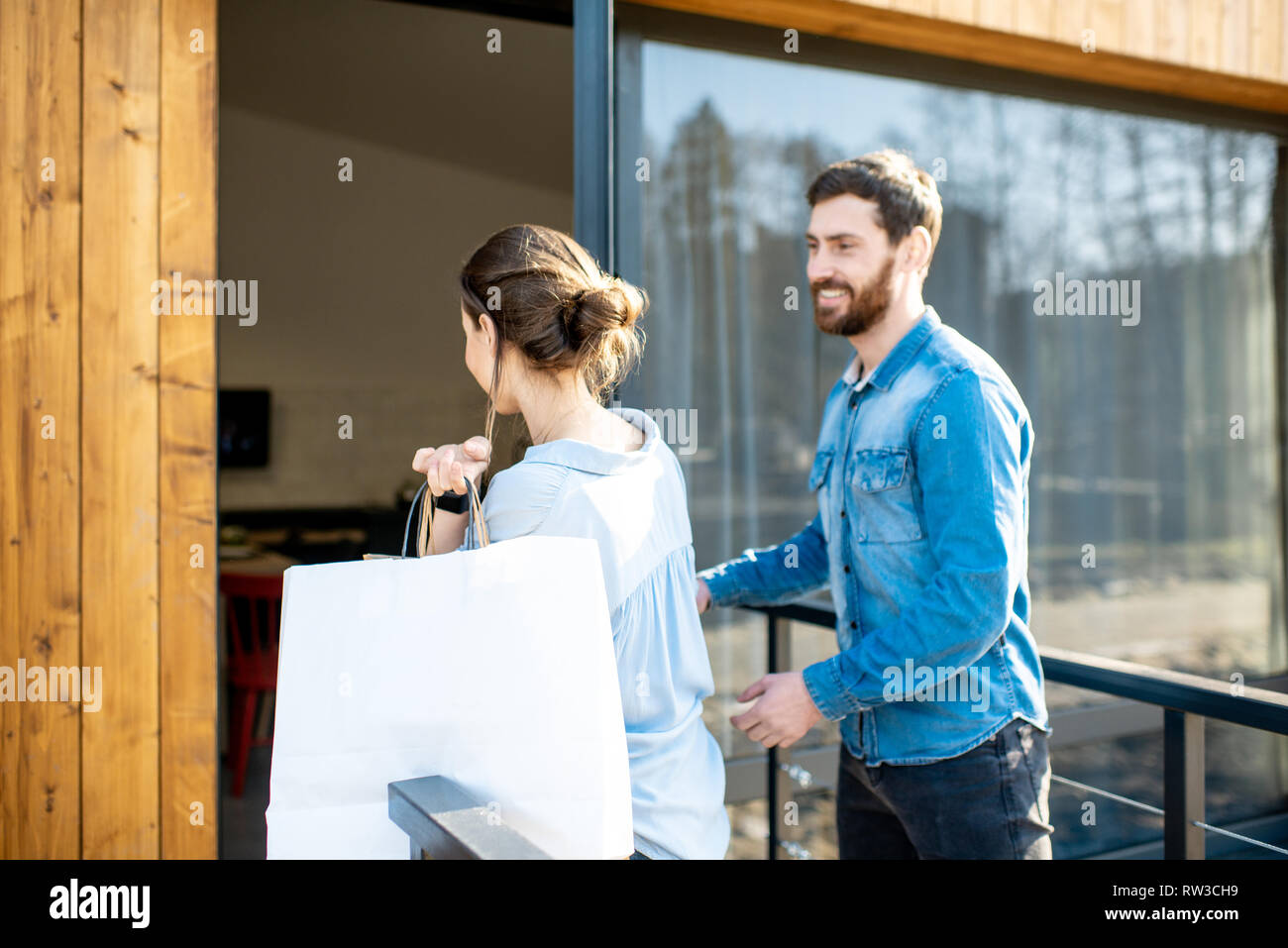 Young couple entering home carrying shopping bags. Happy purchase and modern living concept Stock Photo