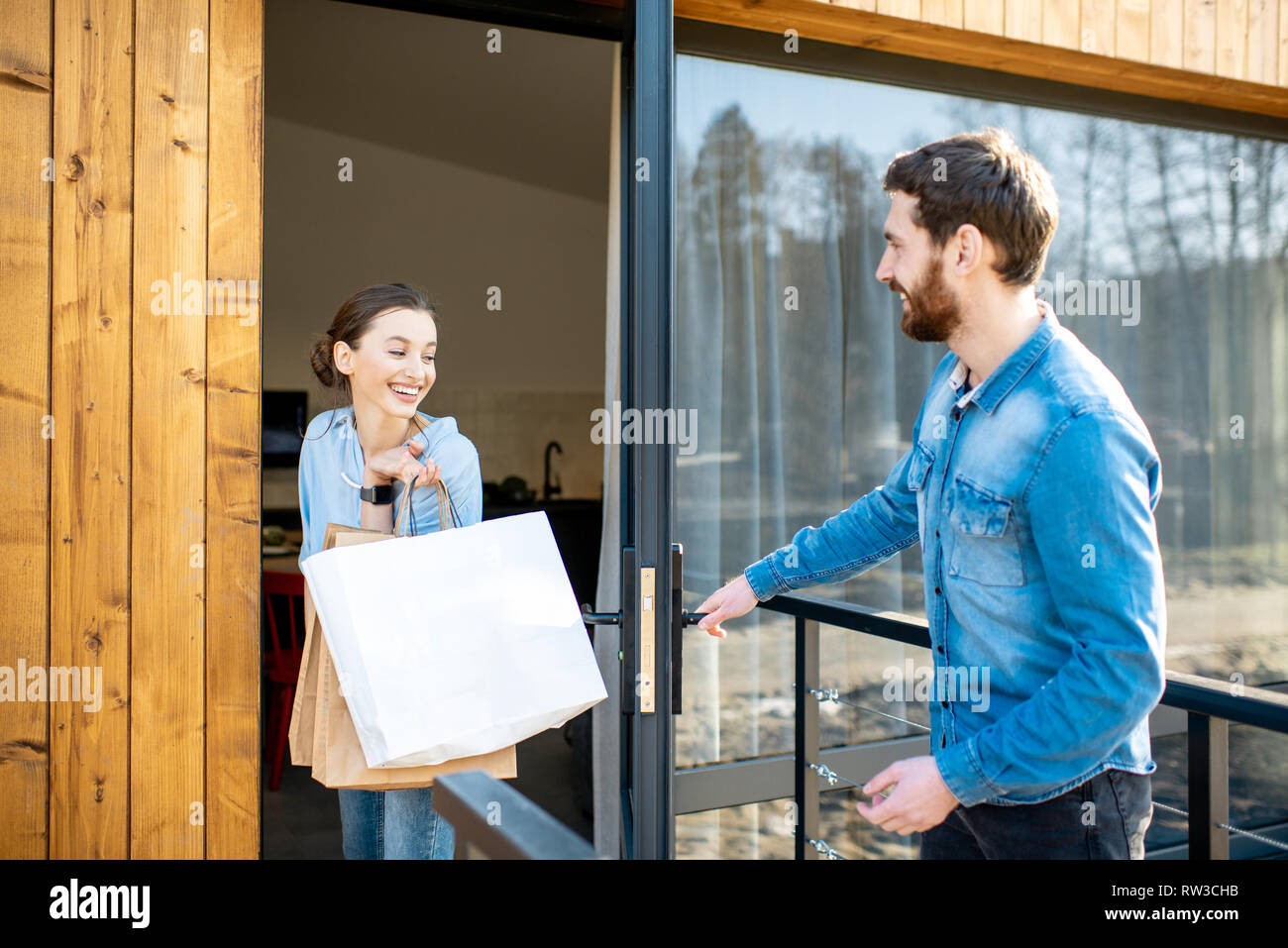 Young couple entering home carrying shopping bags. Happy purchase and modern living concept Stock Photo