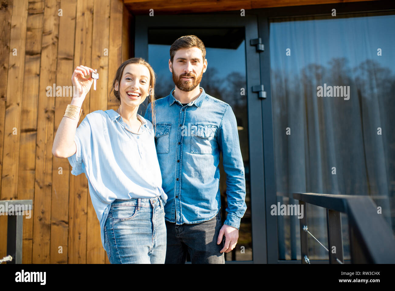 Portrait of a young and happy couple standing together in front of ...