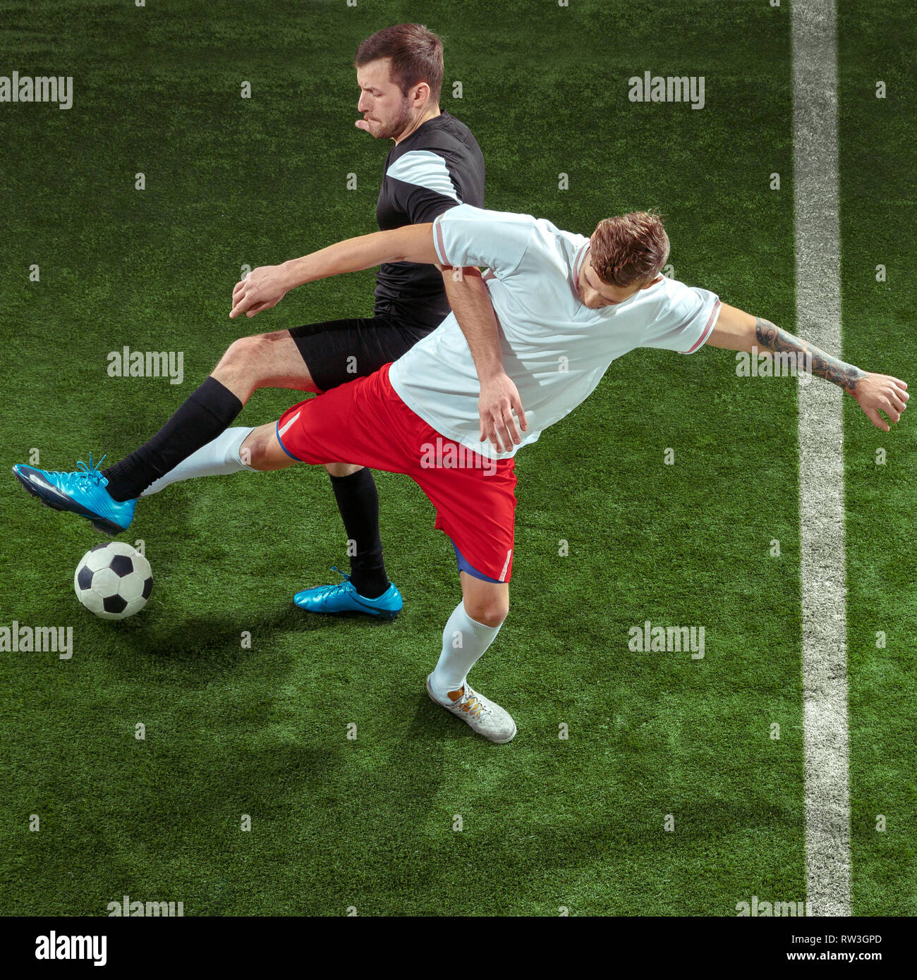 Football player tackling for ball over green grass background. Professional  male soccer players in motion at stadium. Fit jumping men in action, jump,  movement at game Stock Photo - Alamy