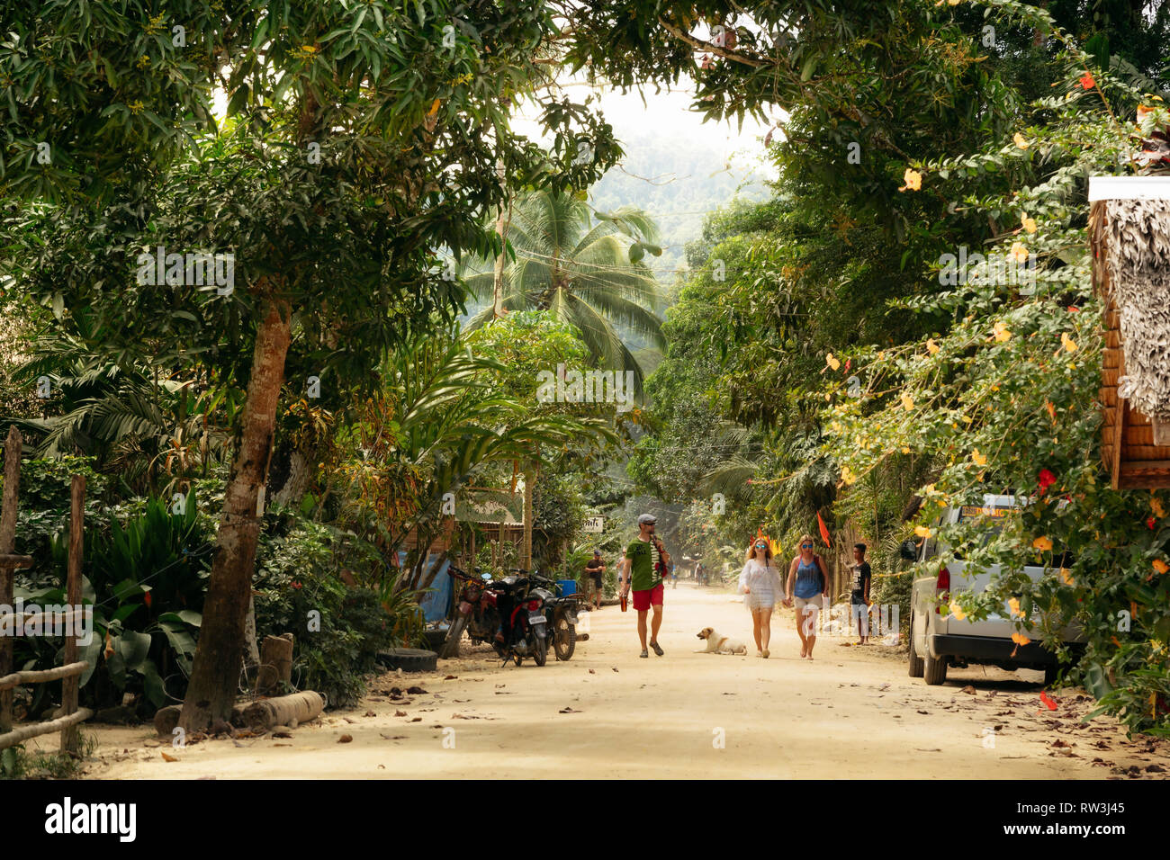 Port Barton, Palawan, Philippines - February 3, 2019: People walk along street with dirt road in traditional Philippine village Stock Photo