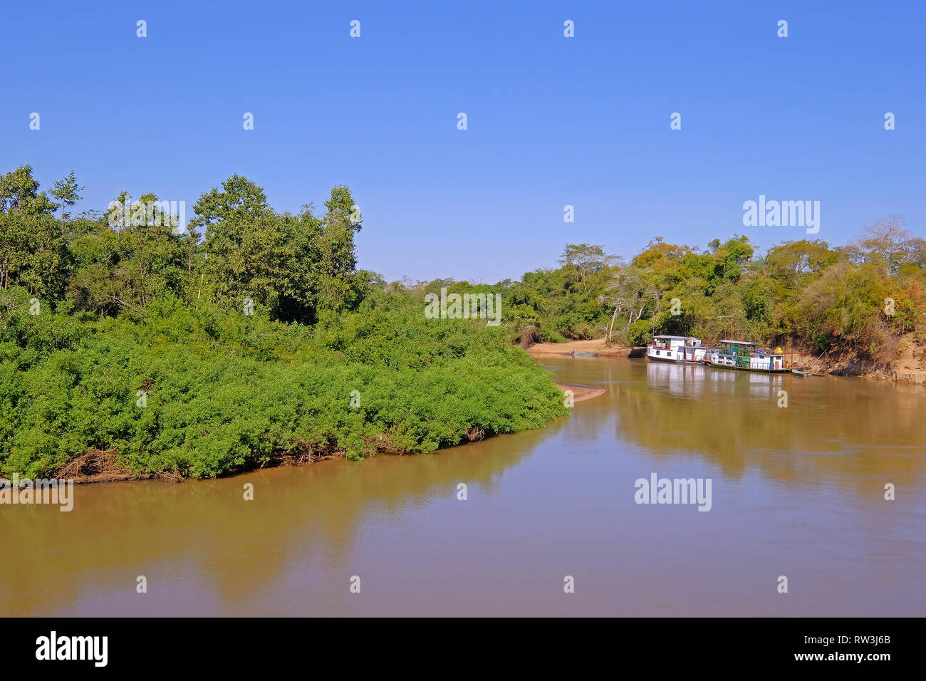 Densely forested shores of the Aquidauana river in the brazilian Pantanal, houseboats on the riverbank, Brazil Stock Photo