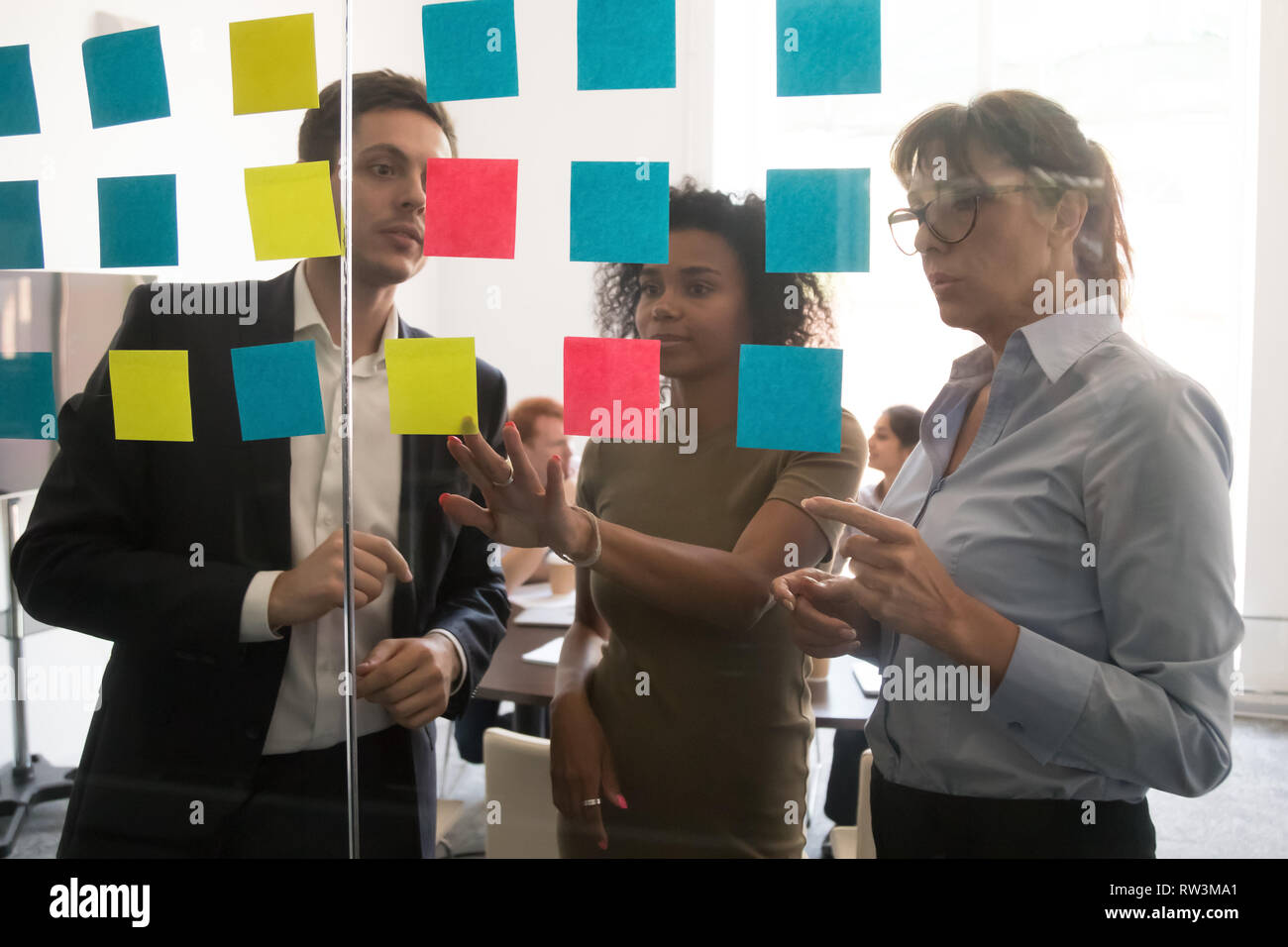 Serious multicultural business team discussing project plan with sticky notes Stock Photo