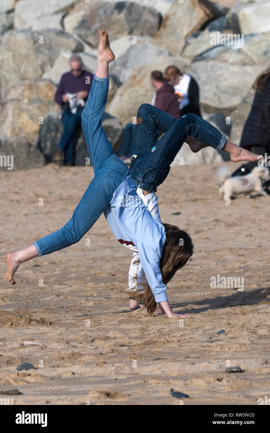 Young energetic teenage girls doing handstands on Fistral Beach in Newquay Cornwall. Stock Photo