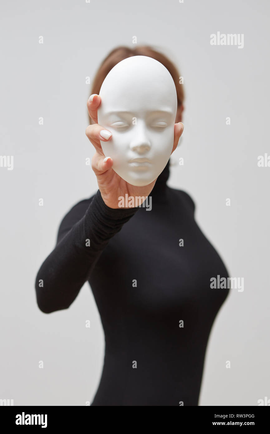 Young woman in a black sweater with plaster mask in her hand instead of