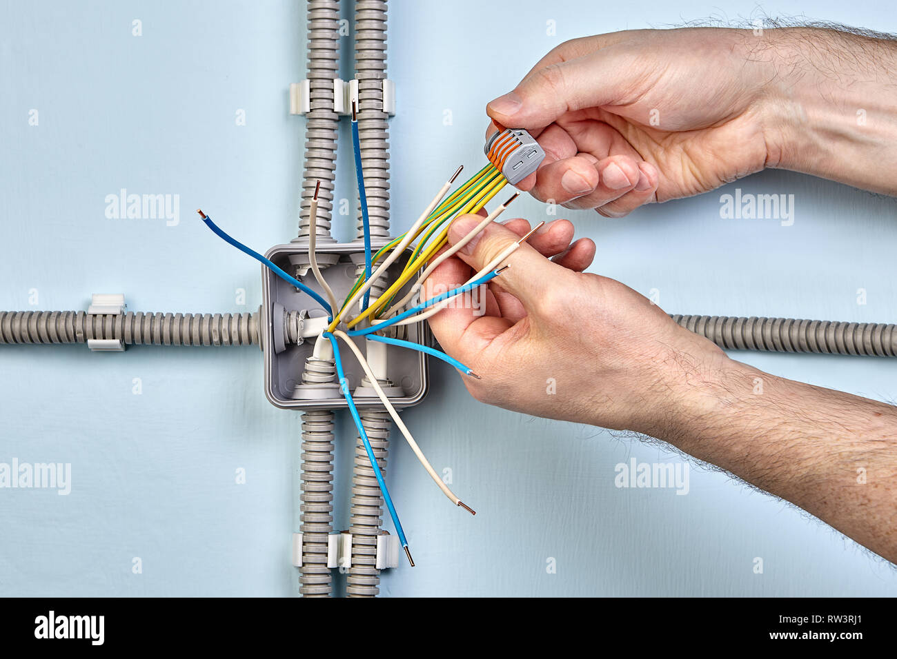 Electrician uses spring terminals to bind wires together durind mounting electrical junction box. Stock Photo