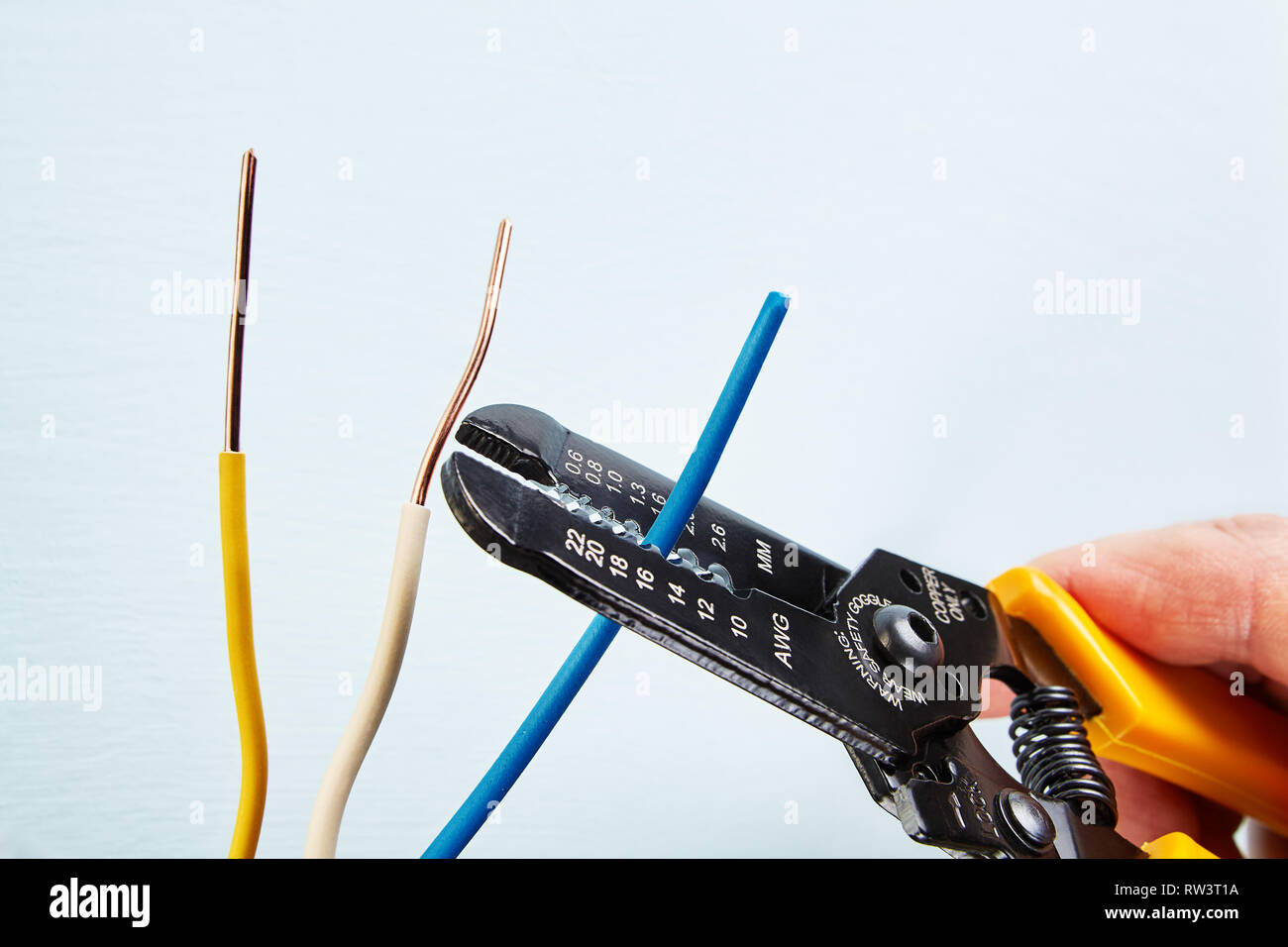 Electrician uses wire stripper tool during electrical wiring services