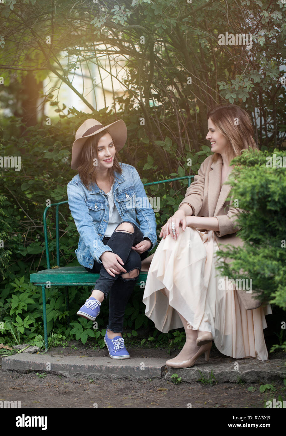 Pretty women talking on greenery foliage background, lifestyle portrait Stock Photo