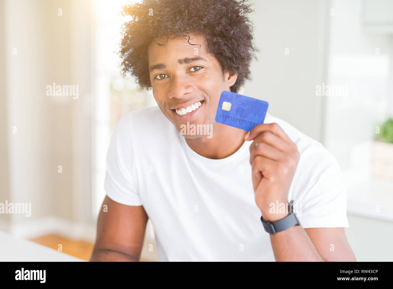 African American man holding credit card with a happy face standing and ...