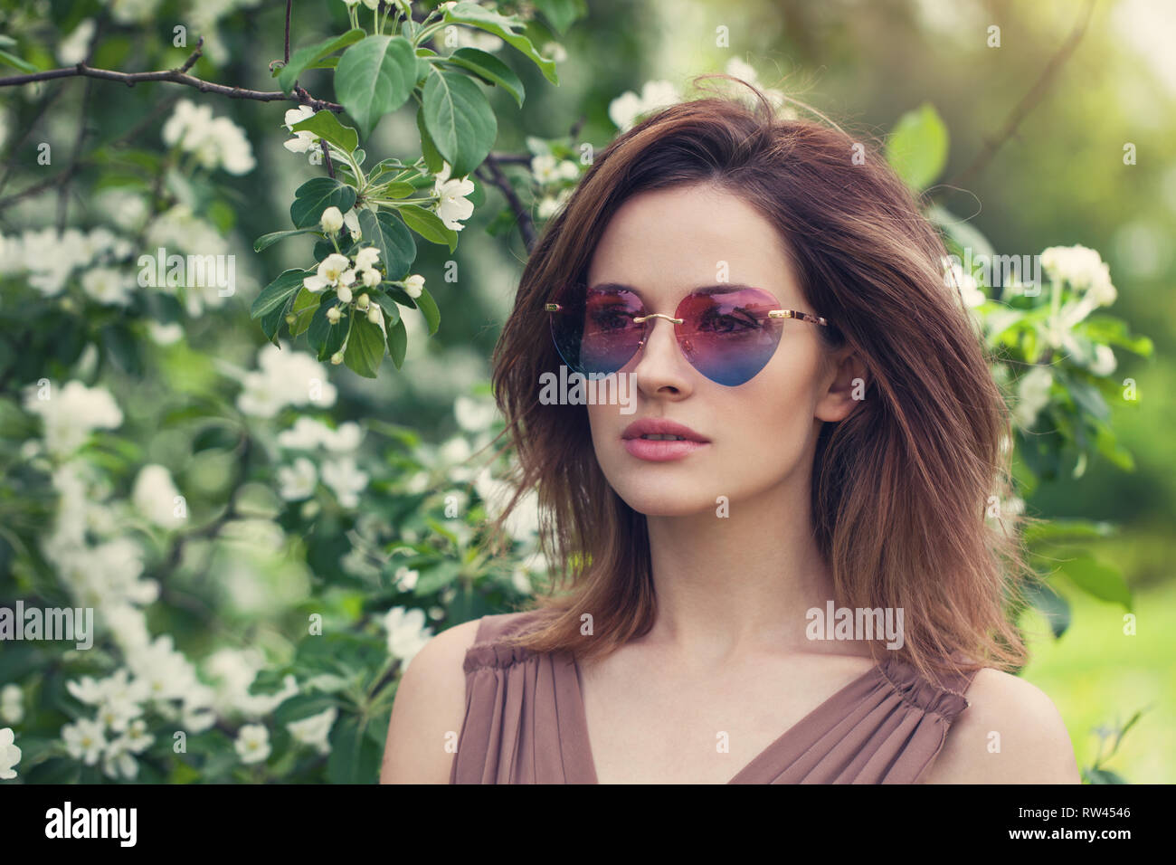Young beautiful woman in sunglasses outdoors. Cute girl with brown layered hair,  spring portrait Stock Photo