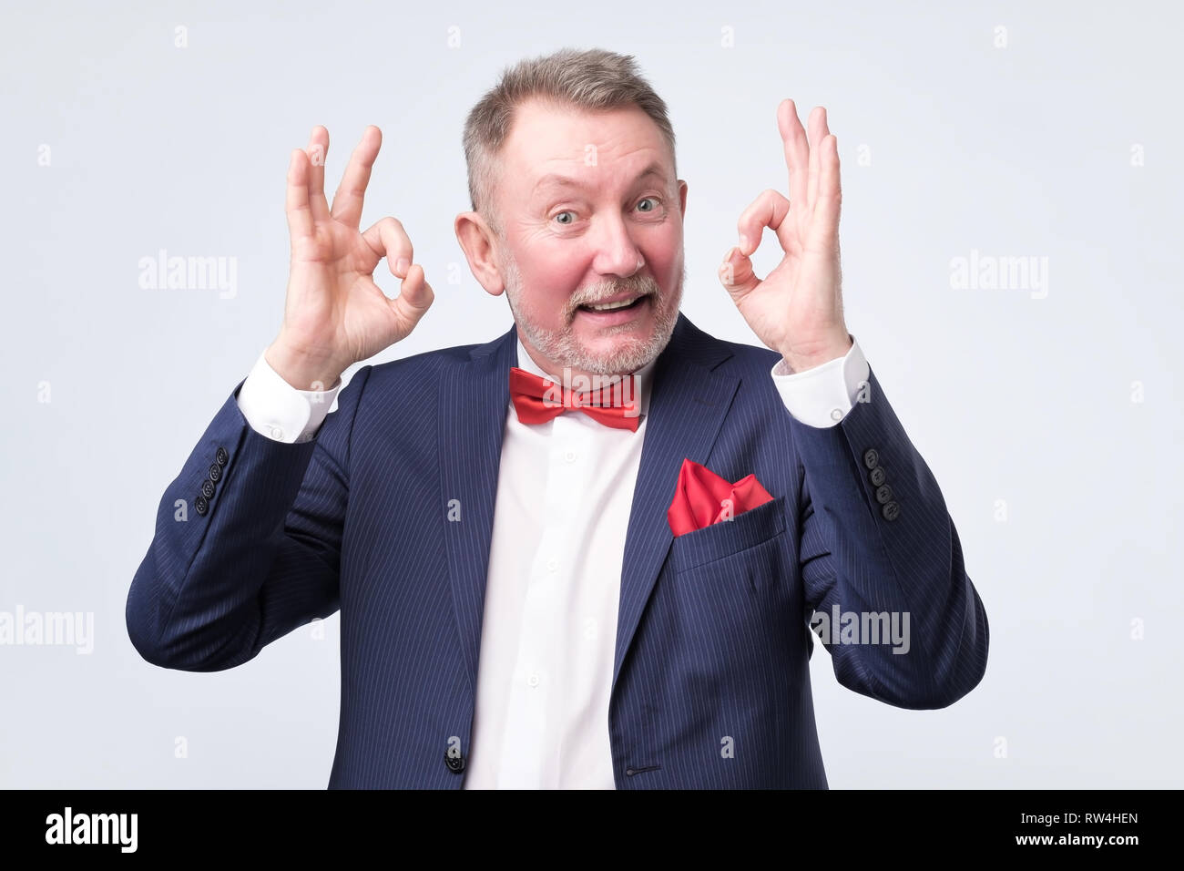 Senior man in elegant blue suit showing OK sign. He is agree with your choice. Positive human emotion. Stock Photo