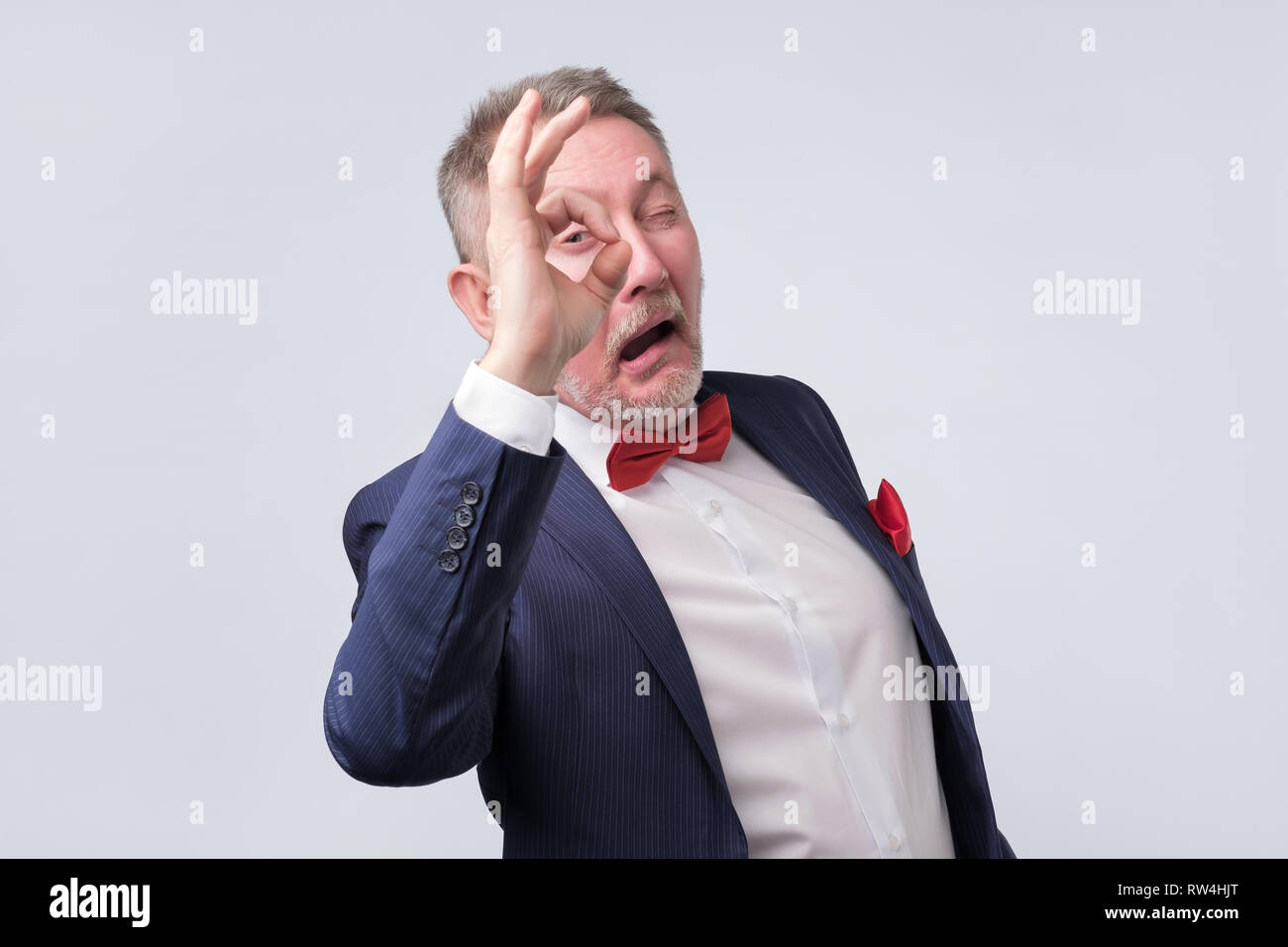 Senior man in elegant blue suit showing OK sign. He is agree with your choice. Positive human emotion. Stock Photo