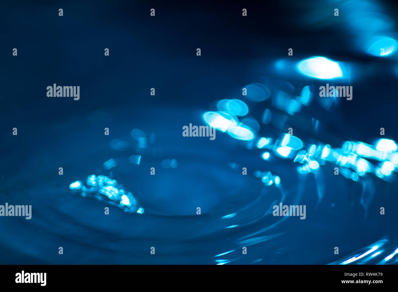 Splash of water drops on a water surface colored with celestial ink. Concept of purity, cleanliness and preservation of non-renewable resources. Abstr Stock Photo