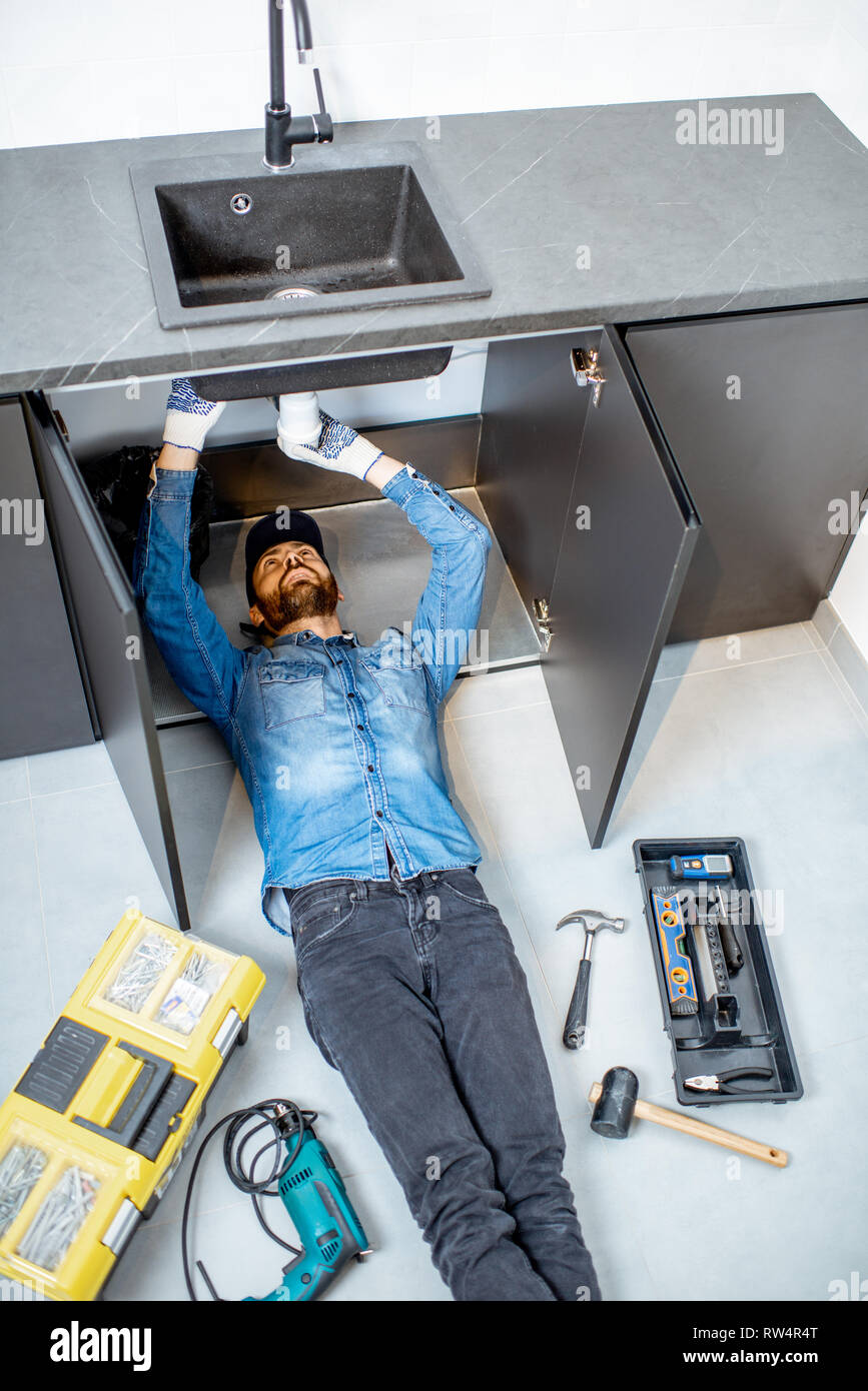 Man Repairing Plumbing Under Sink High Resolution Stock Photography and