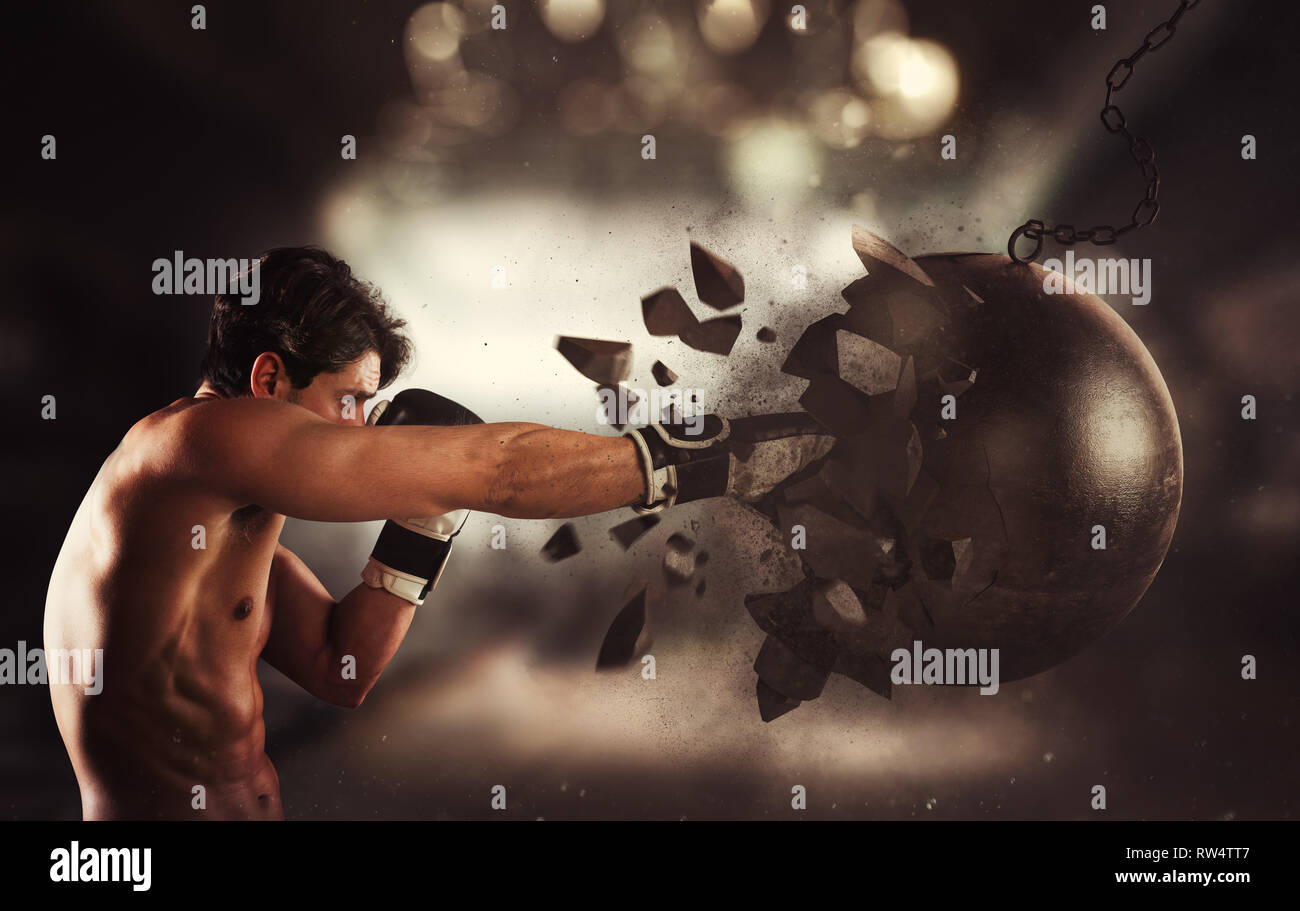 Power and determination of a young muscular boxer against a wrecking ball Stock Photo