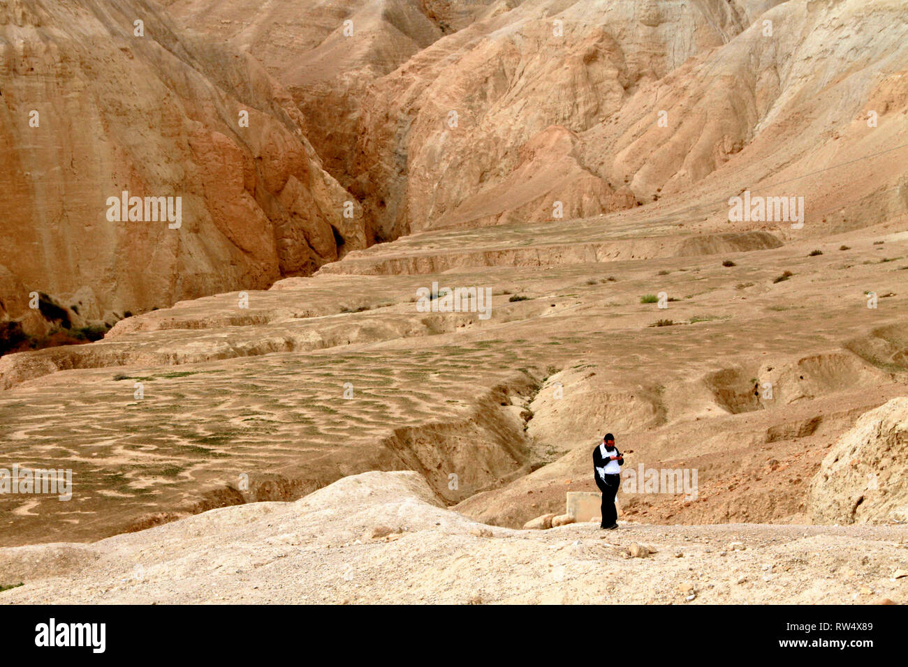 A solitary man walks a trail in barren desert hills. Stock Photo