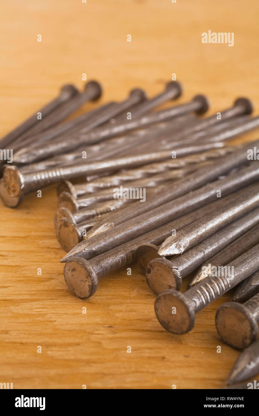 Closeup of steel nails on a plywood floor inside residential home