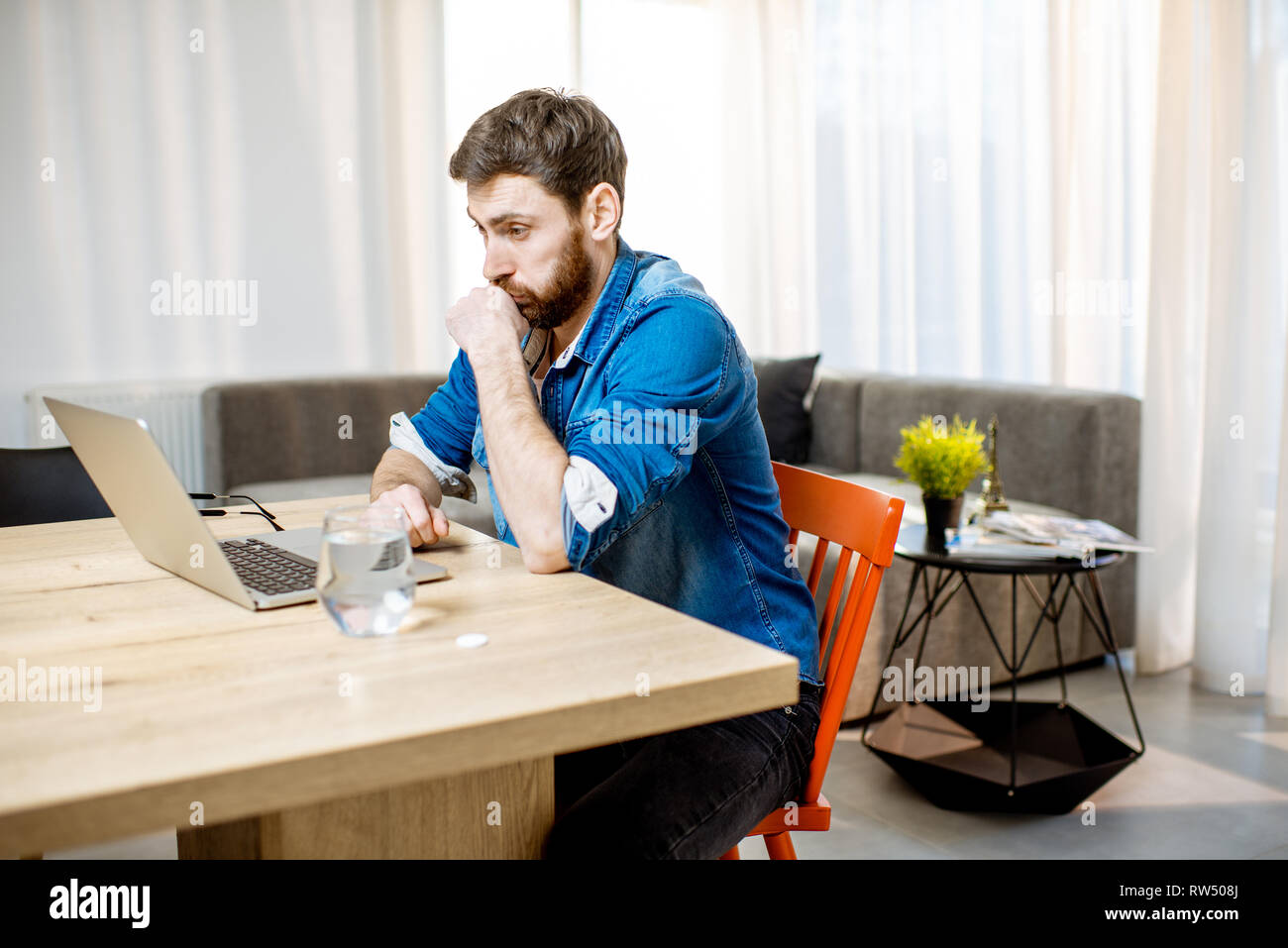 Hanndsome man feeling sick while working on the laptop at the table at home Stock Photo