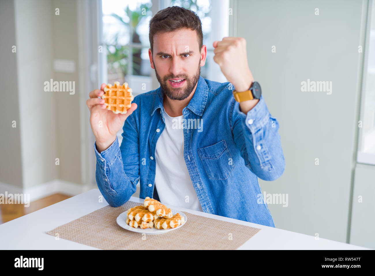 Handsome man eating sweet Belgian pancakes annoyed and frustrated ...