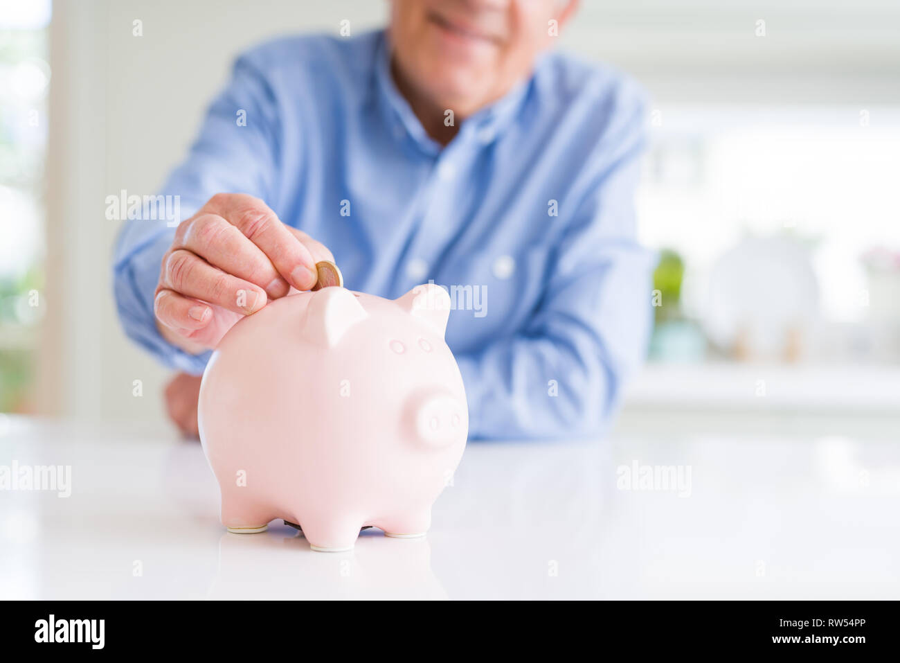 Man putting a coin inside piggy bank as savings smiling confident Stock ...
