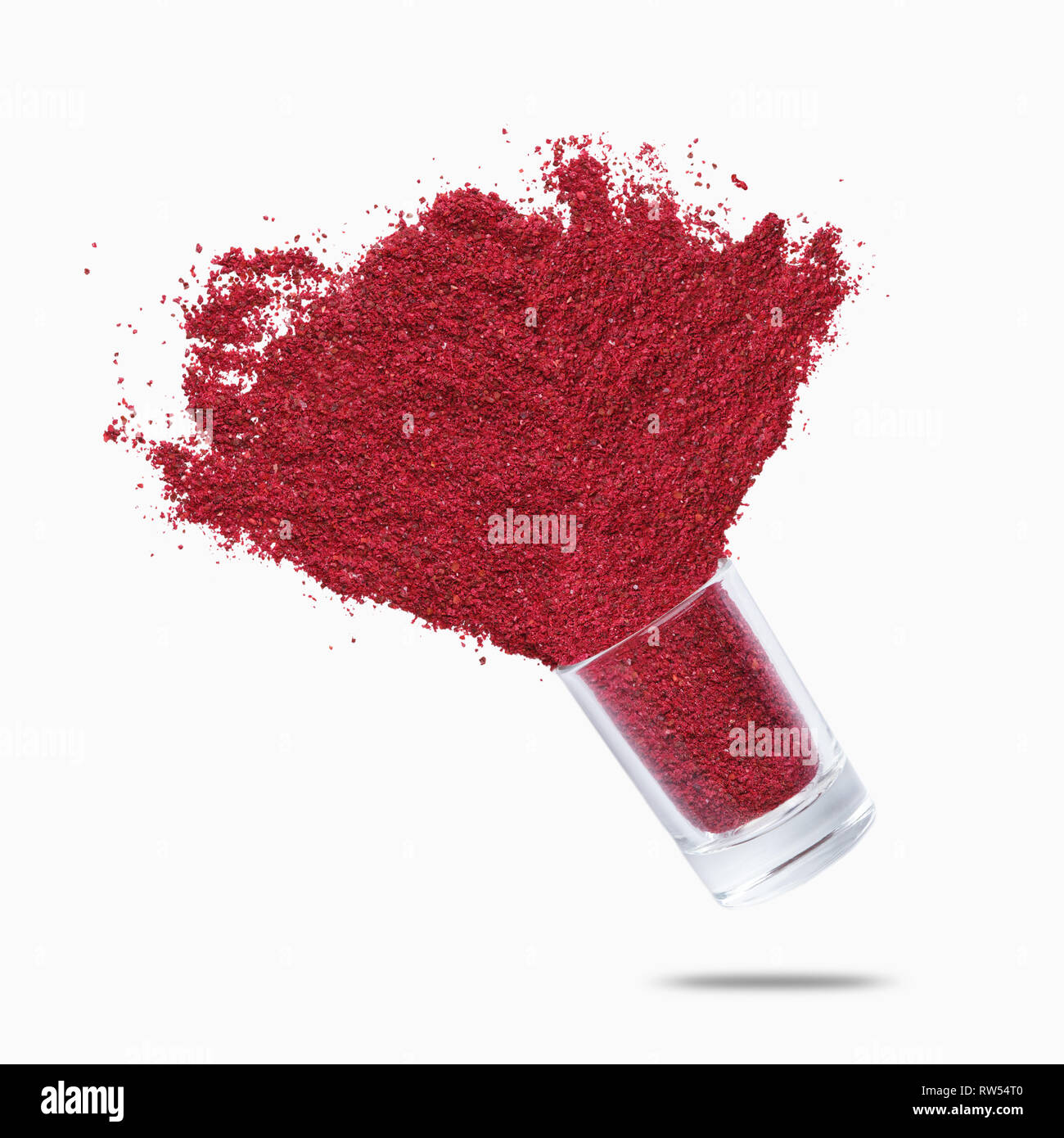 Glass jar with sumac flying on white background Stock Photo - Alamy