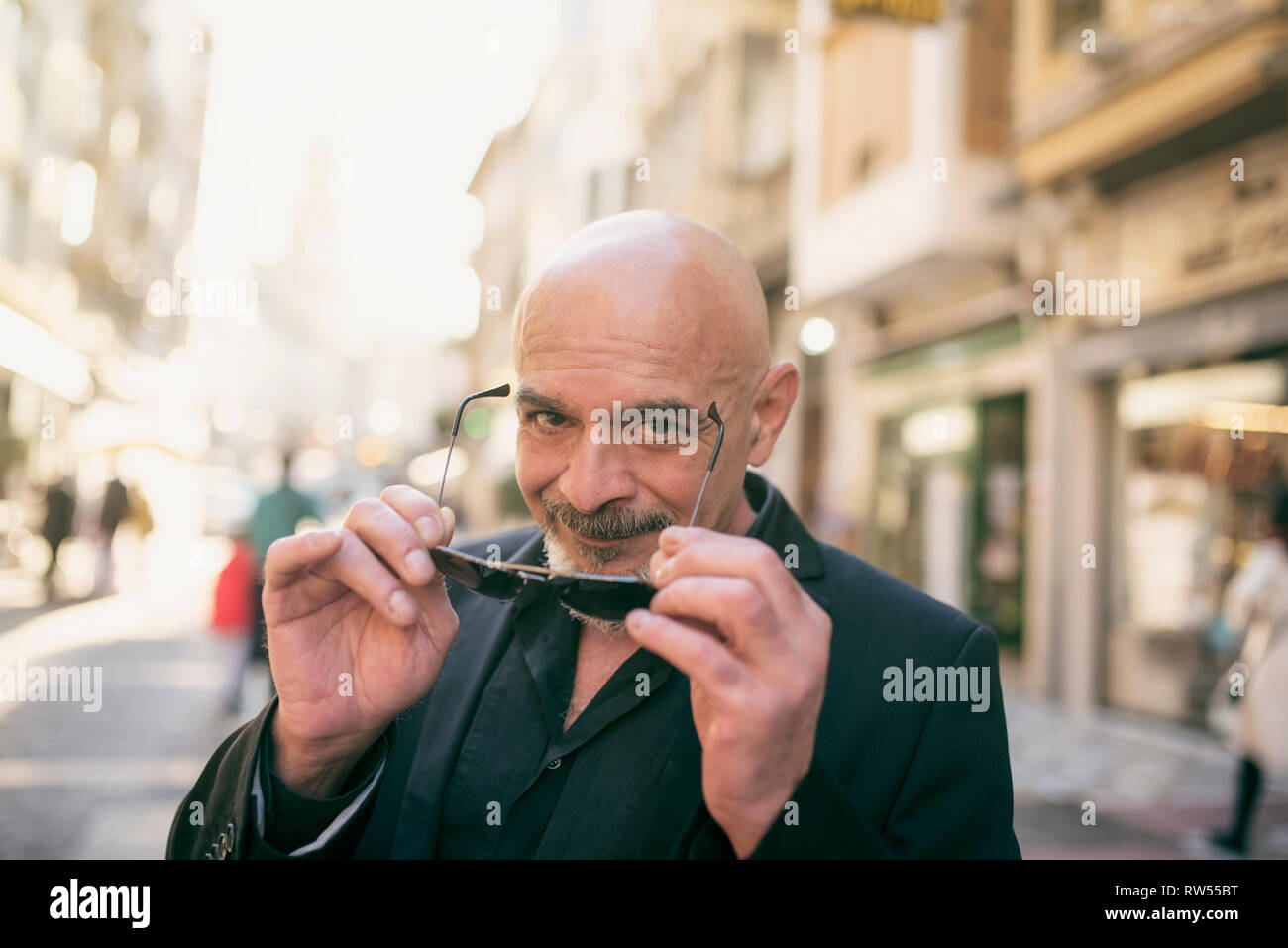 Senior man in the street with her sunglasses looking at camera smiling Stock Photo