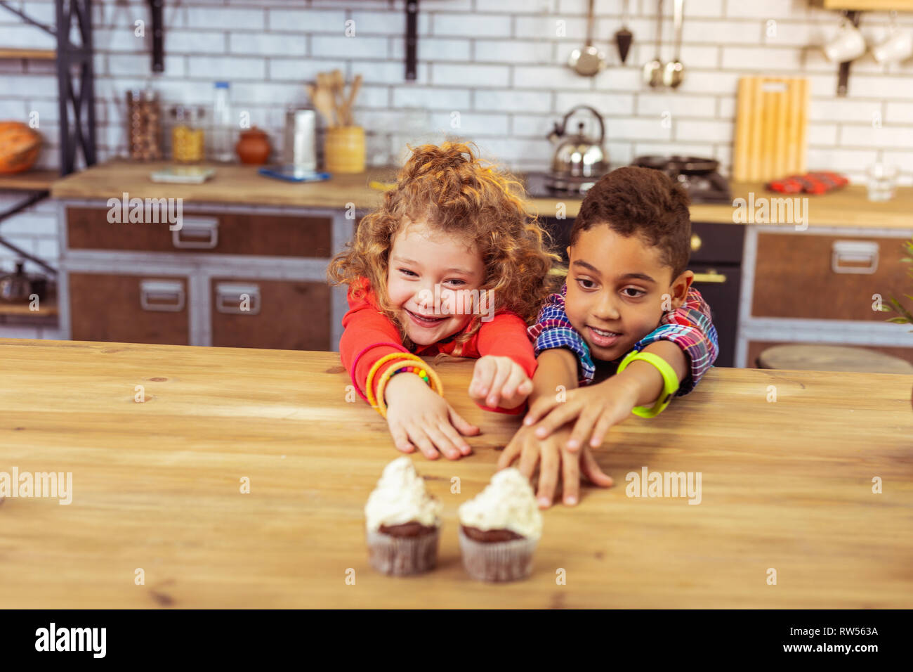 Positive delighted children stretching arms to desserts Stock Photo - Alamy