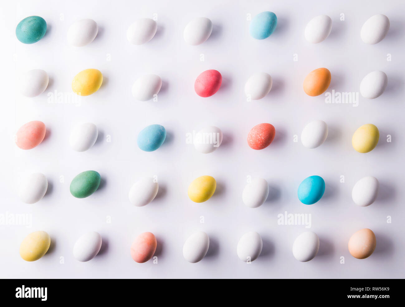 Colored eggs flat lay on a white background. Easter and spring ...